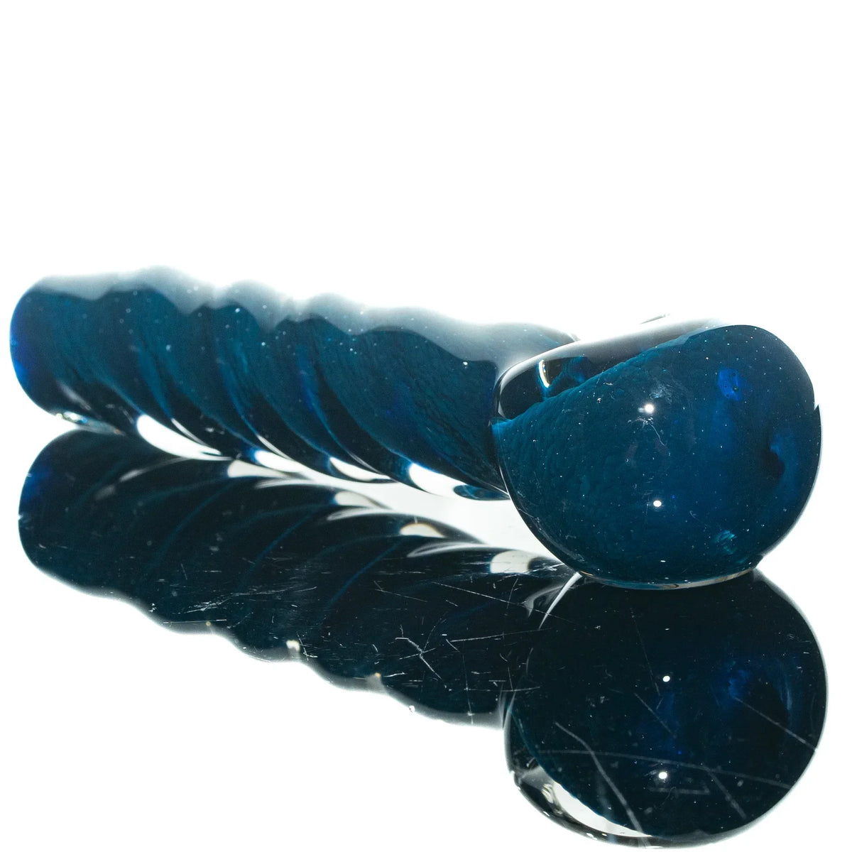Hand-blown blue glass spoon pipe with twisted frit design on reflective surface