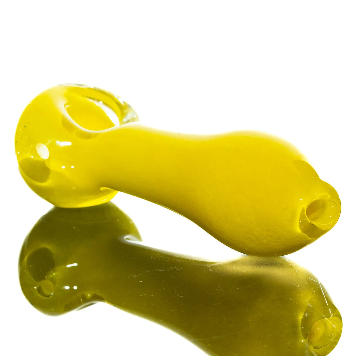 Yellow glass hand pipe with rounded bowl on reflective surface