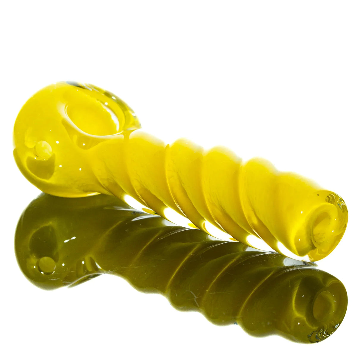 Yellow glass spoon pipe with twisted design, reflected on a white surface