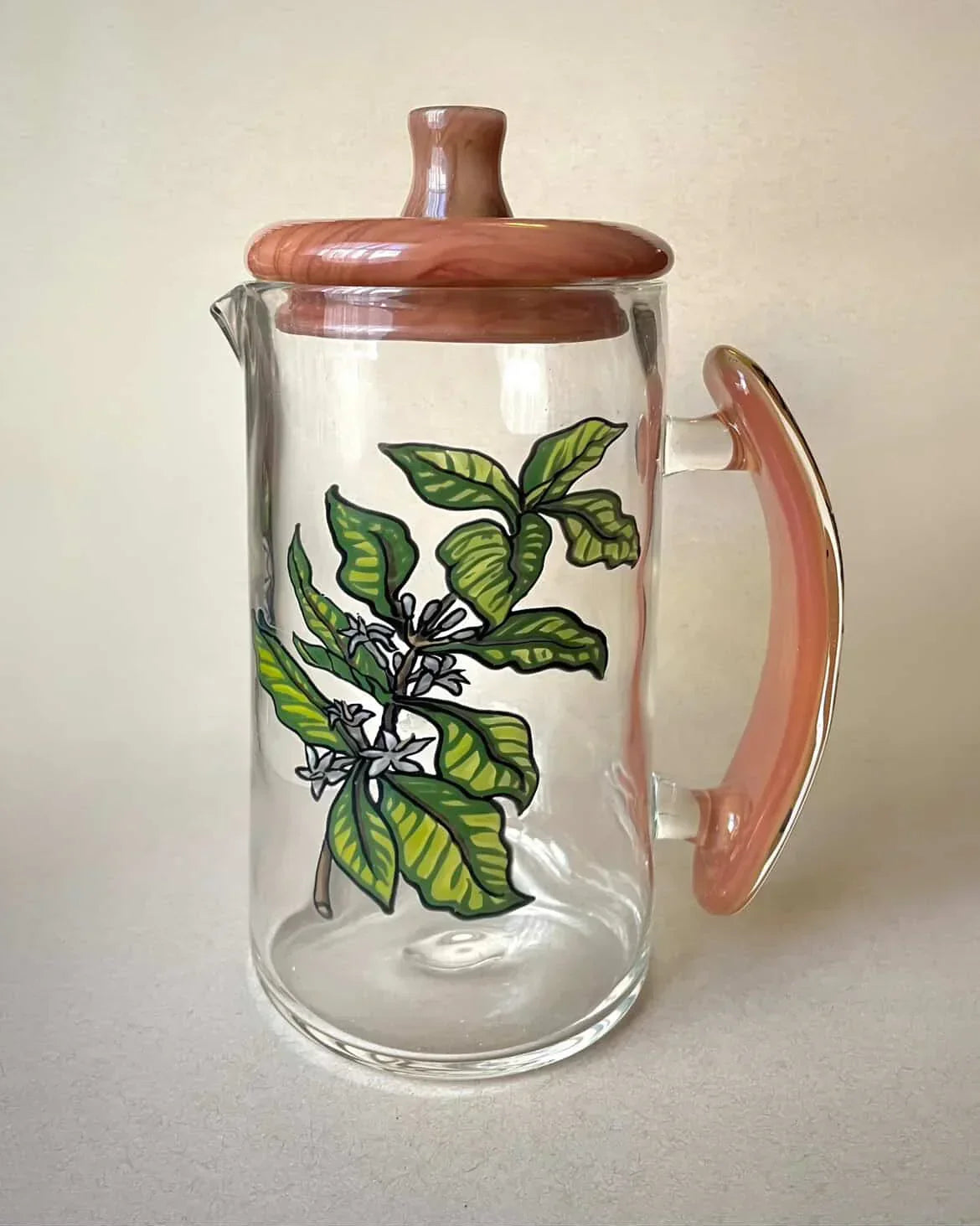 Handcrafted glass jar with pink lid and handle, featuring painted green leaf design