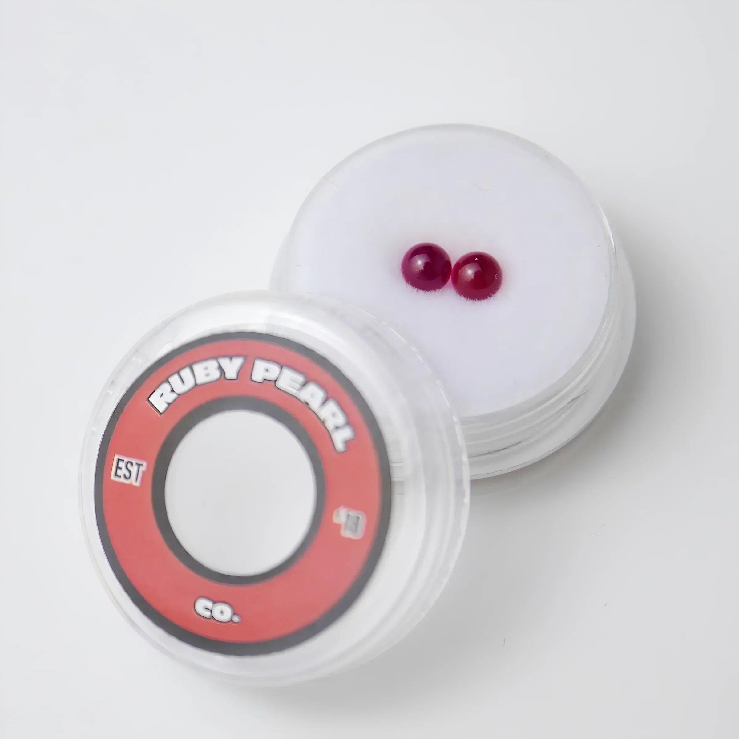 Two ruby terp pearls in display container on white background, ideal for dab rigs or vaporizer accessories