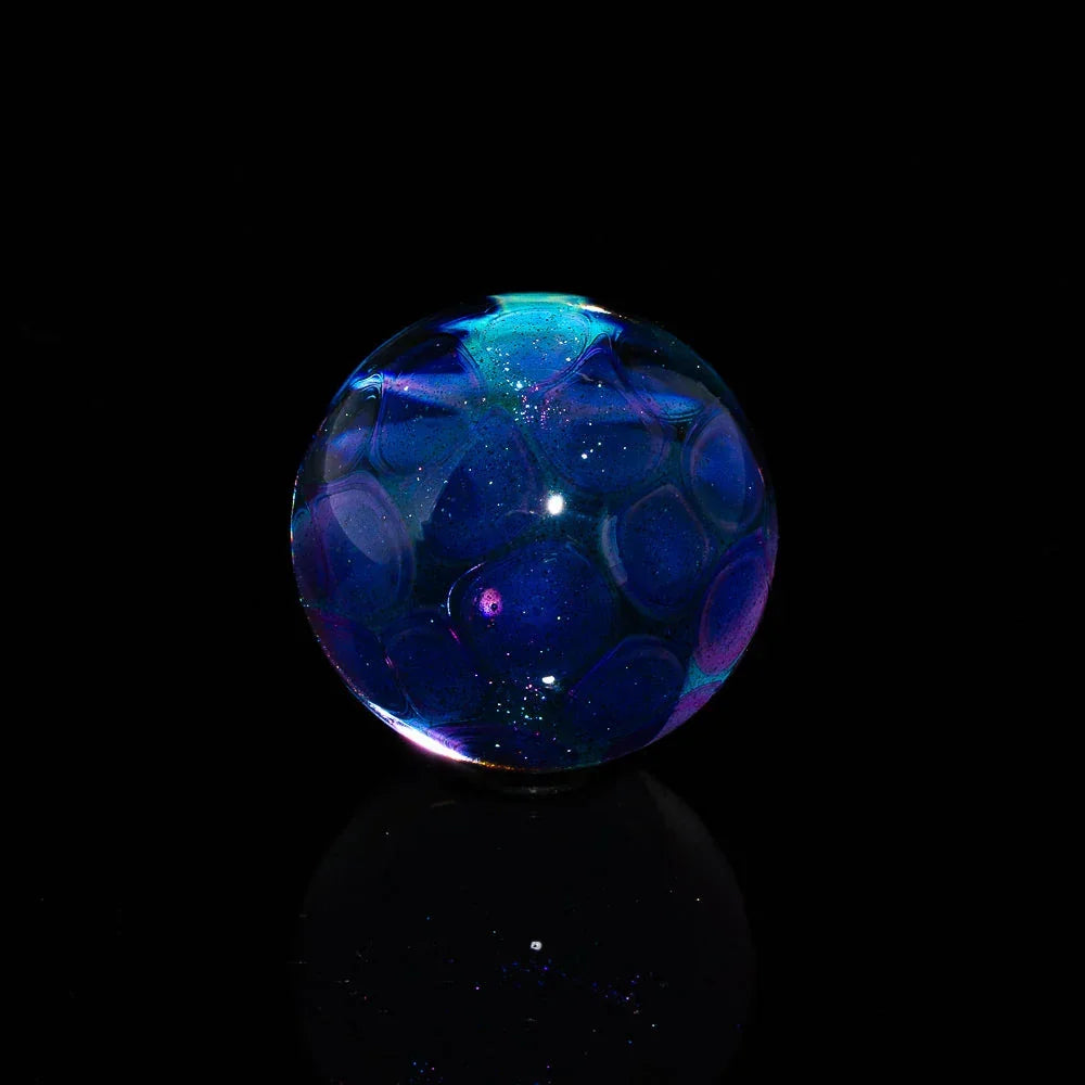 Iridescent blue and purple glass marble with galaxy-like details on a black background