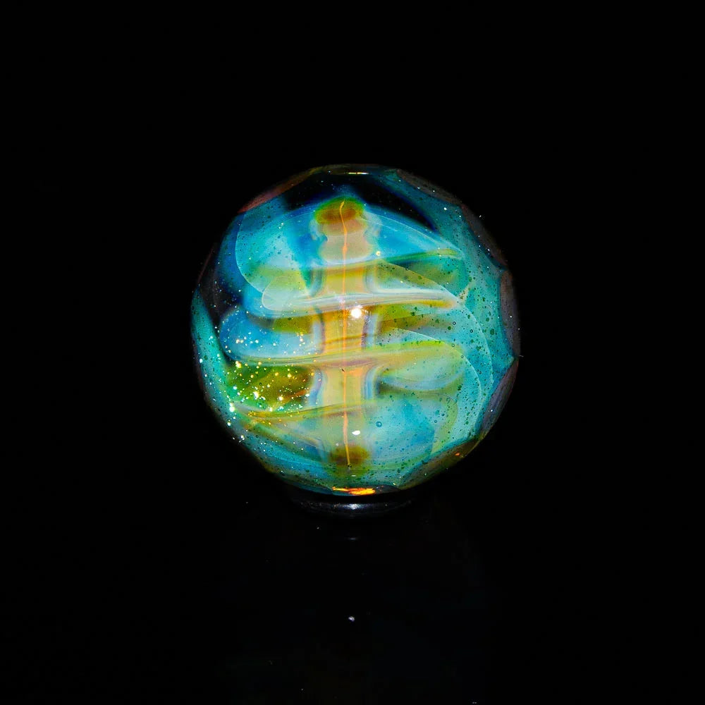 Handcrafted glass marble with swirling blue, green, and gold patterns on a black background