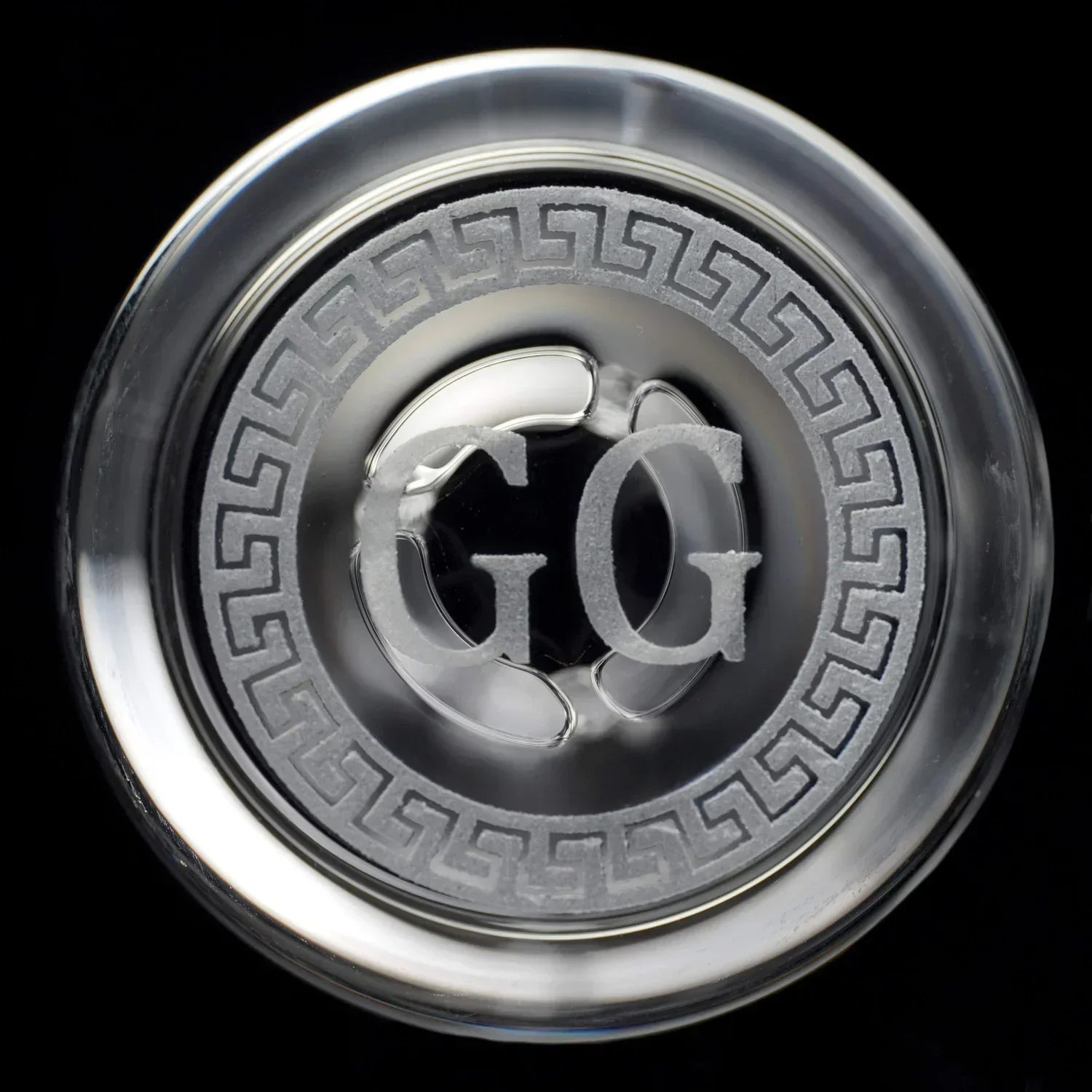 Closeup of etched glass water pipe base with decorative pattern and GG initials
