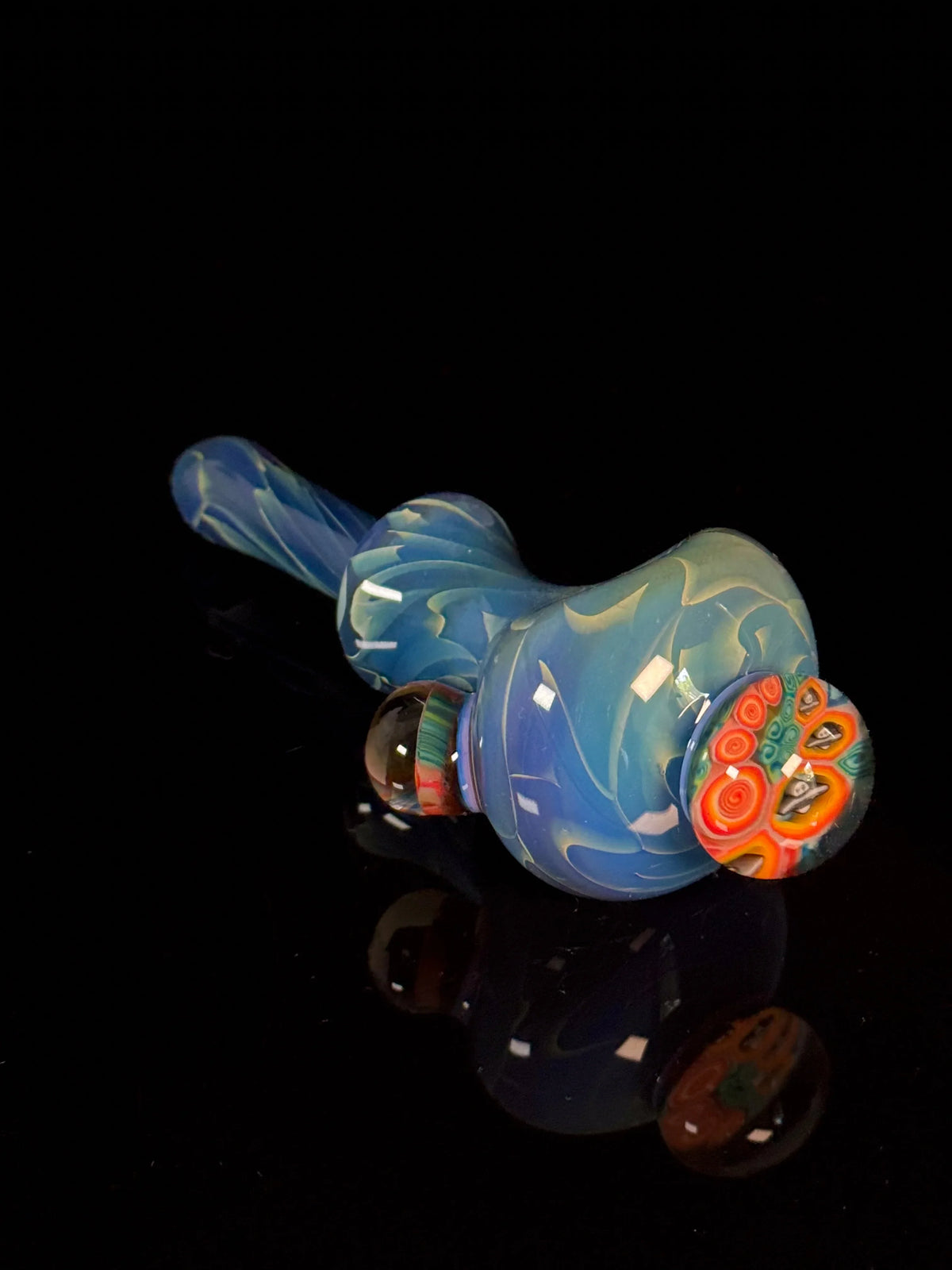 Blue heady glass pipe with colorful marble accents on black background