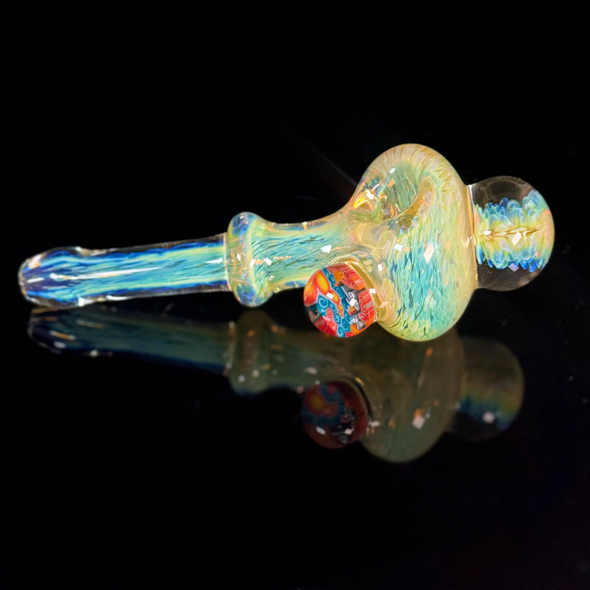 Colorful glass hand pipe with intricate patterns displayed on a reflective black surface