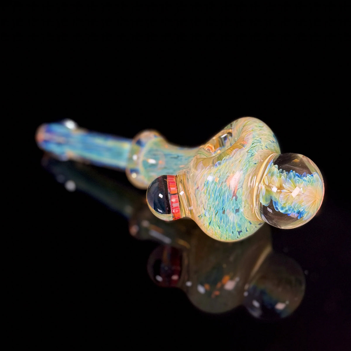 Handcrafted glass pipe with colorful swirling patterns on a black reflective surface