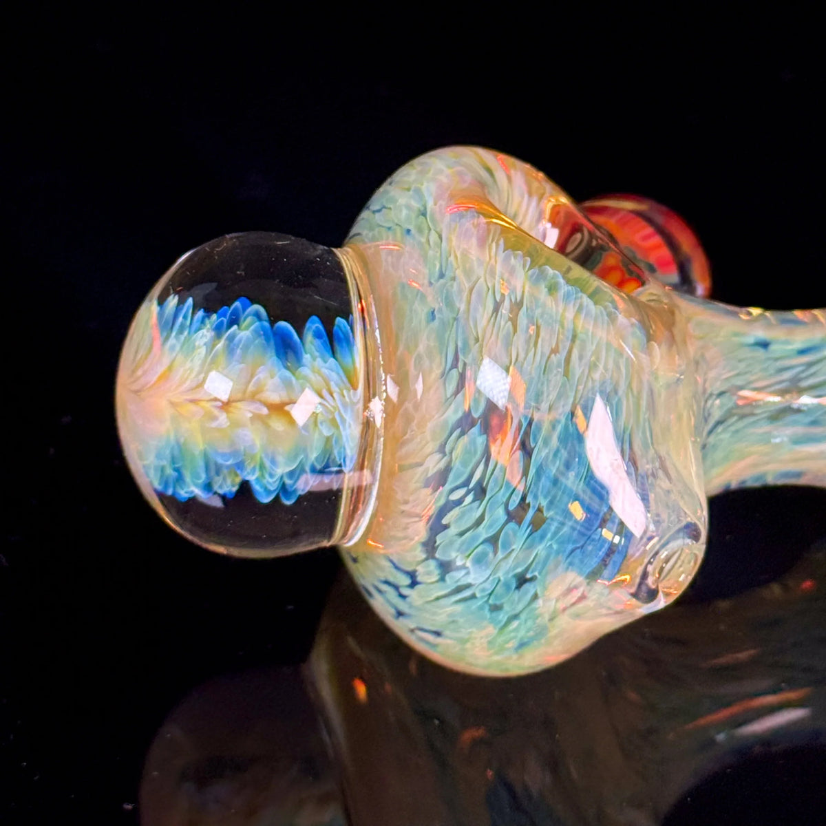 Hand-blown glass pipe with iridescent blue and yellow feather pattern on black background