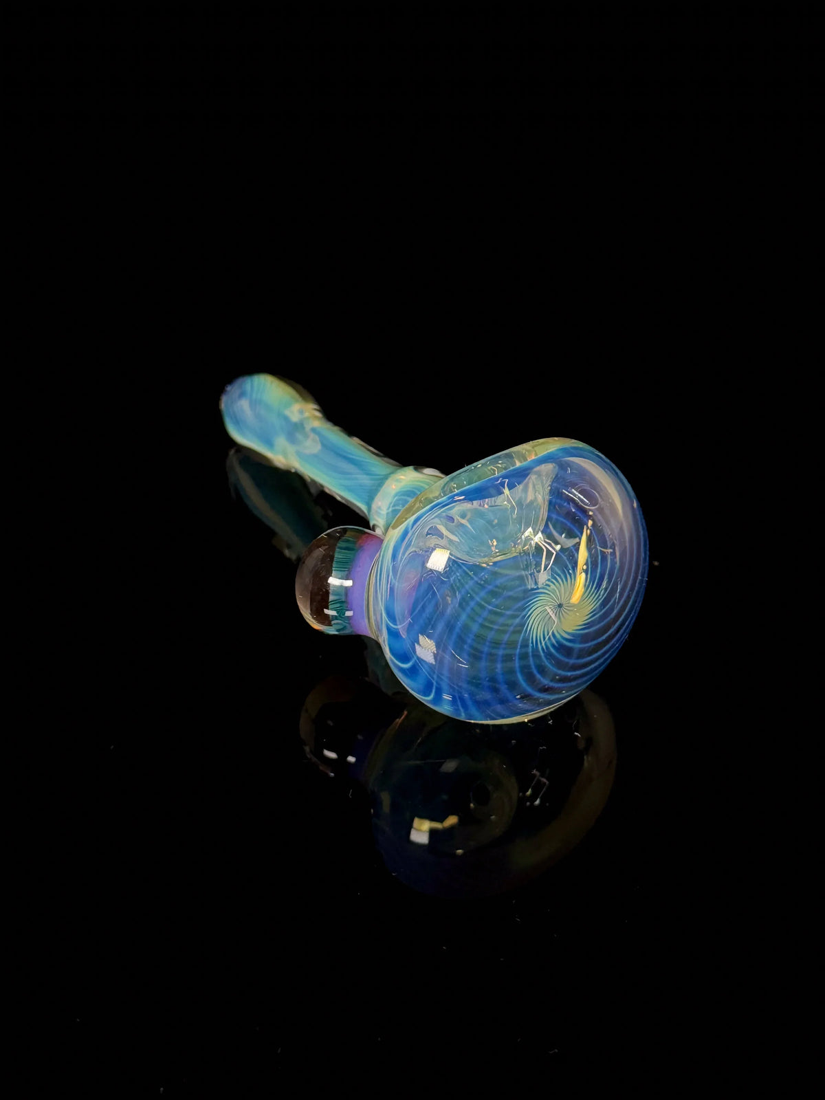 Colorful glass hand pipe with swirling blue and yellow patterns on a black background