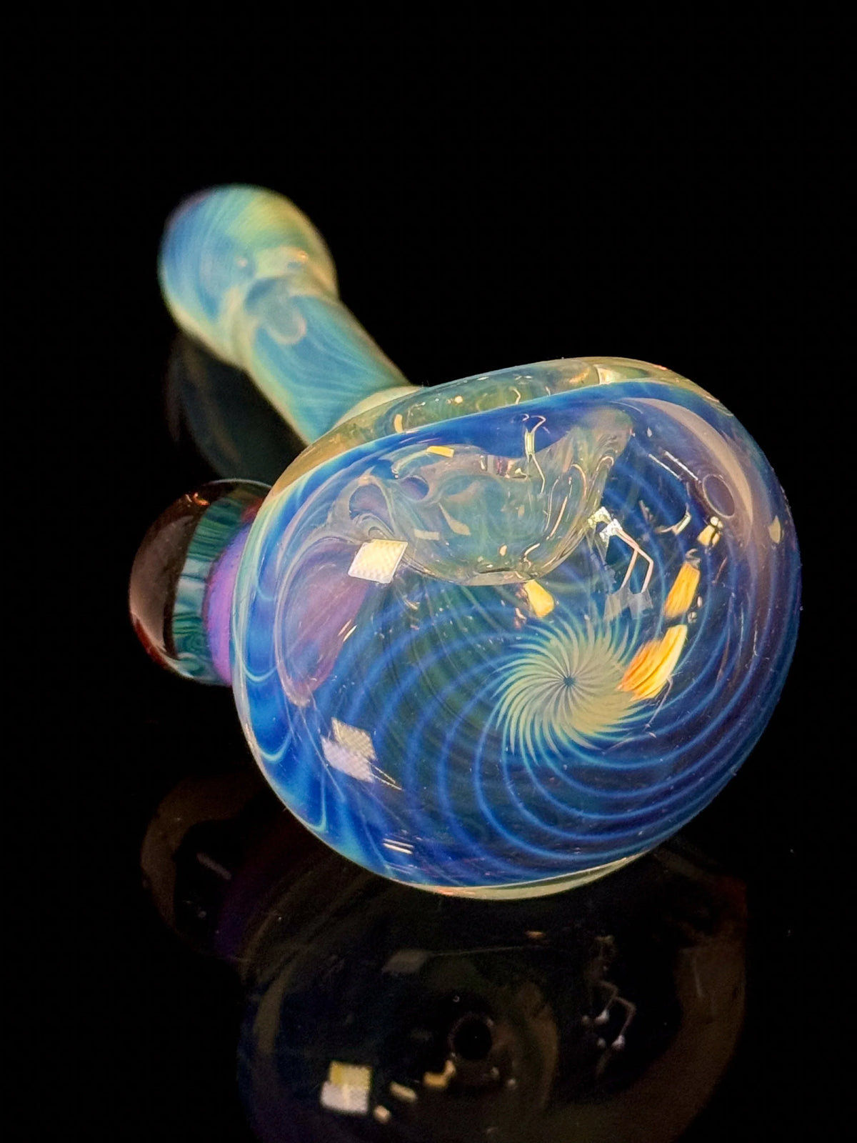 Colorful heady glass hand pipe with intricate blue swirls on a black background