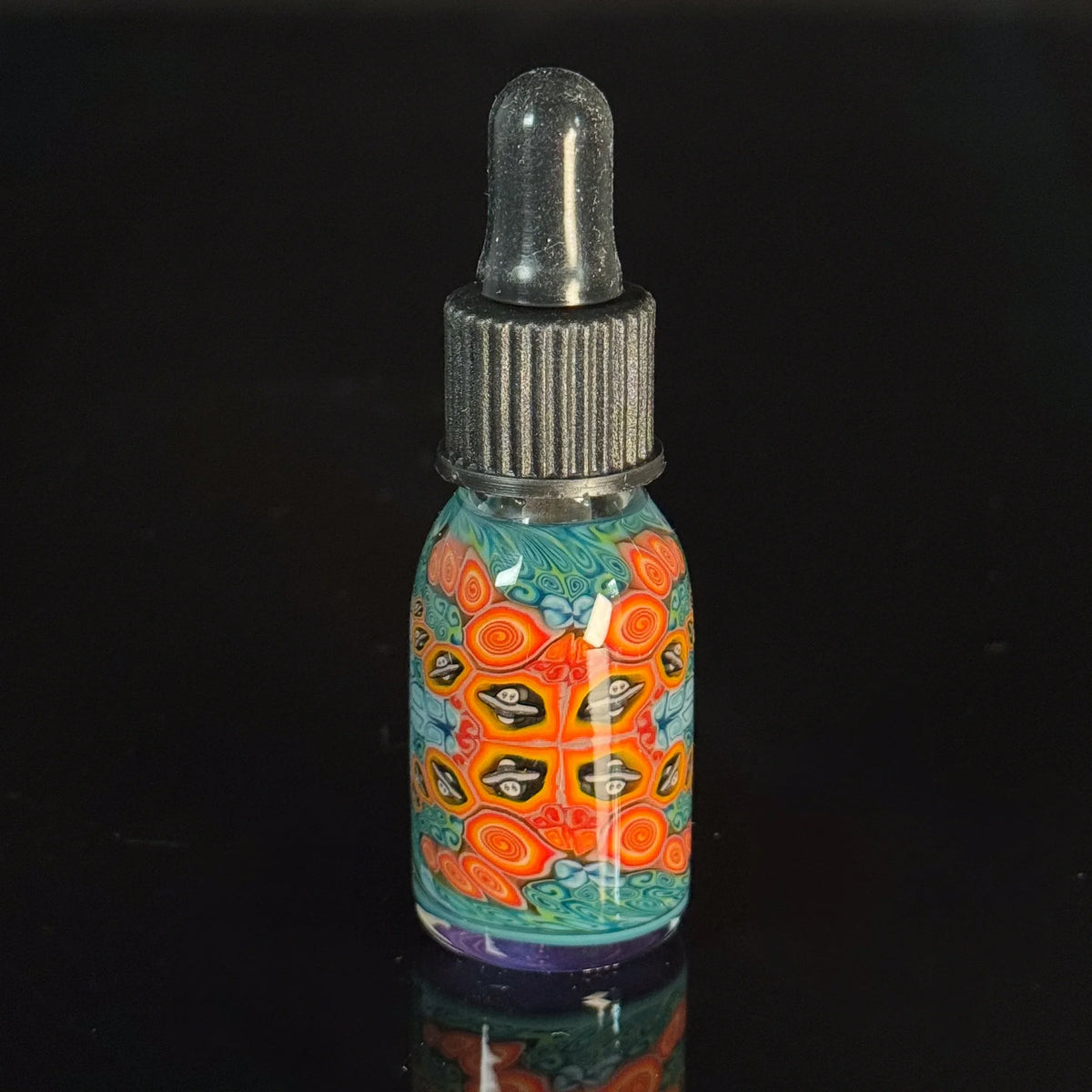 Decorative glass dropper bottle with colorful psychedelic patterns on a black background