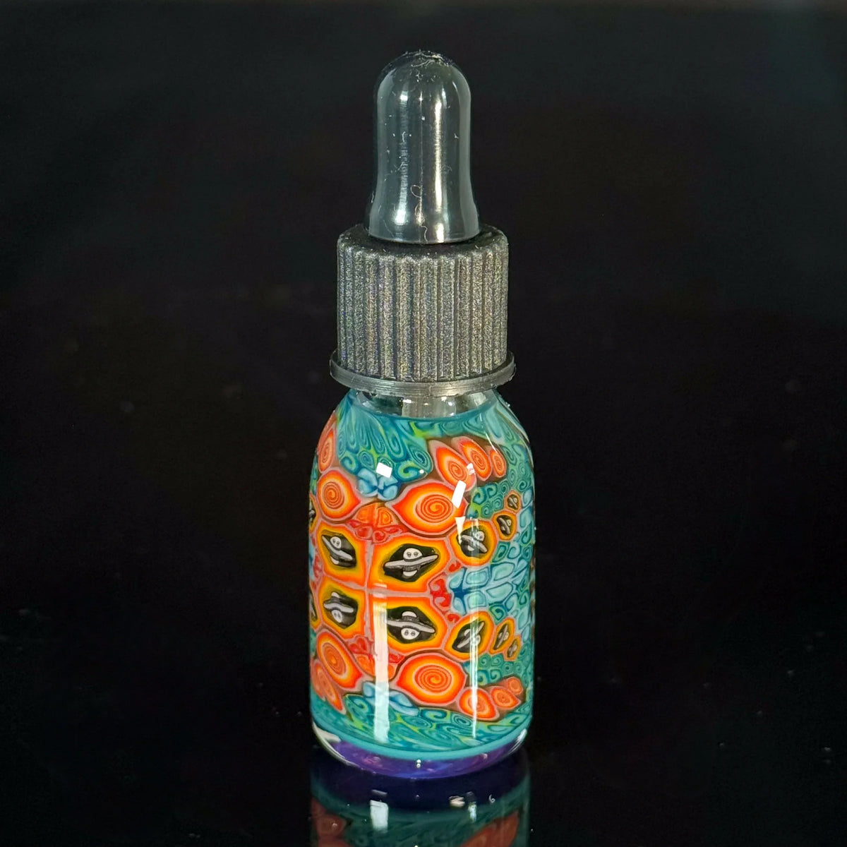 Colorful heady glass dropper bottle with intricate swirl and face designs on black background
