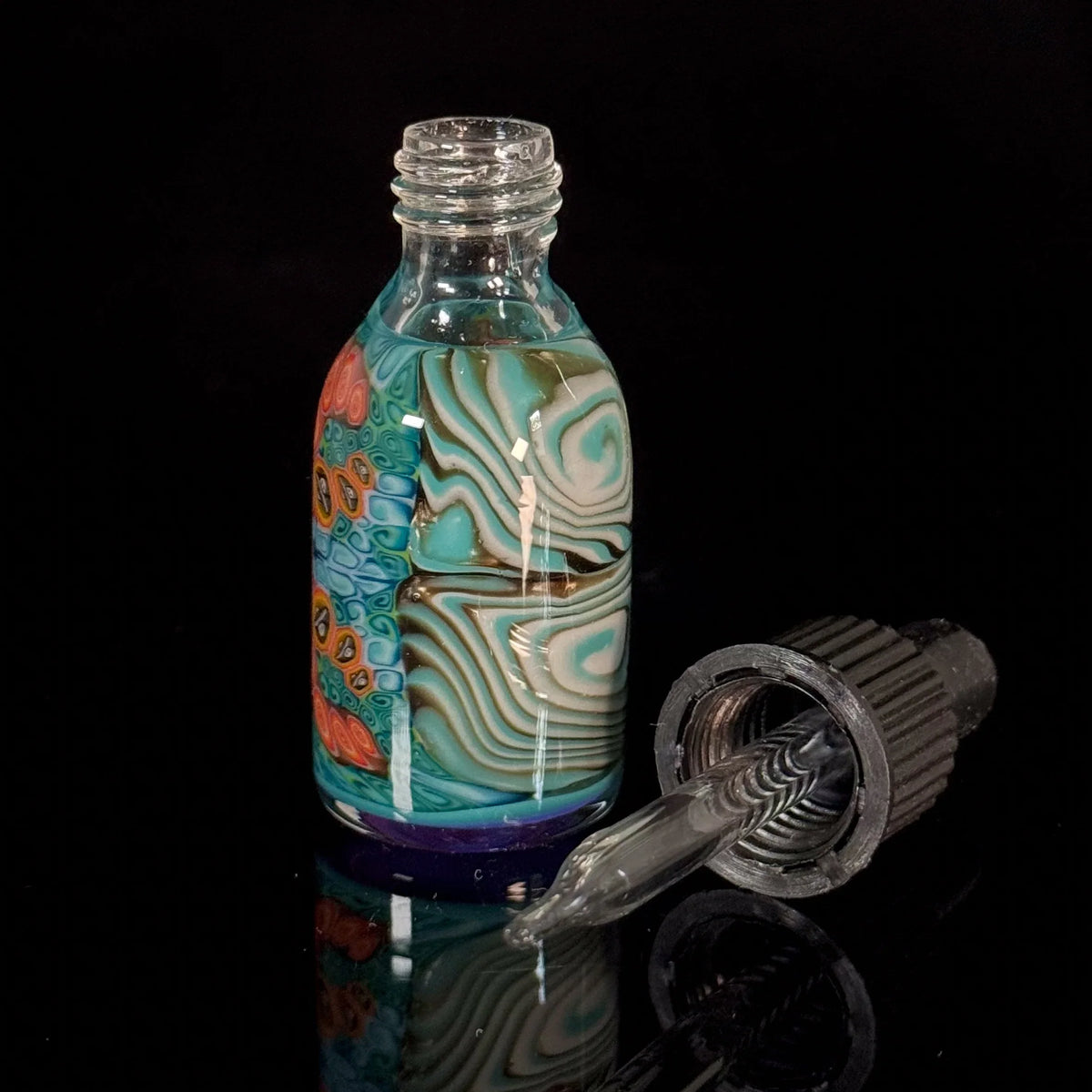 Colorful glass dropper bottle with intricate patterns on black background