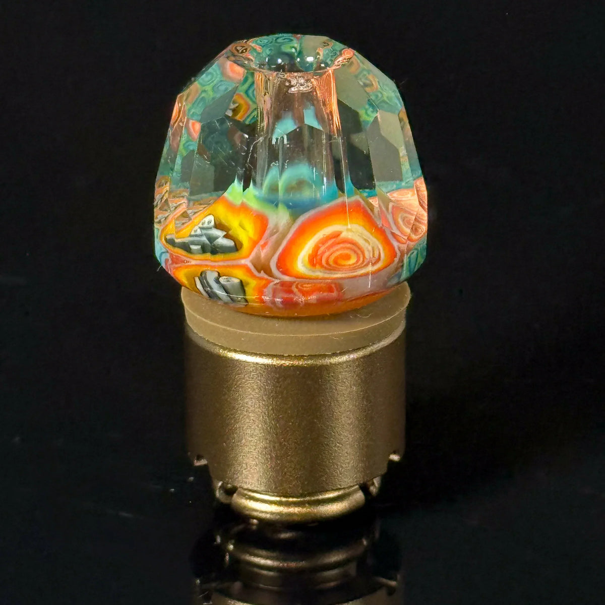 Colorful faceted glass carb cap with swirled patterns for dab rig on black background