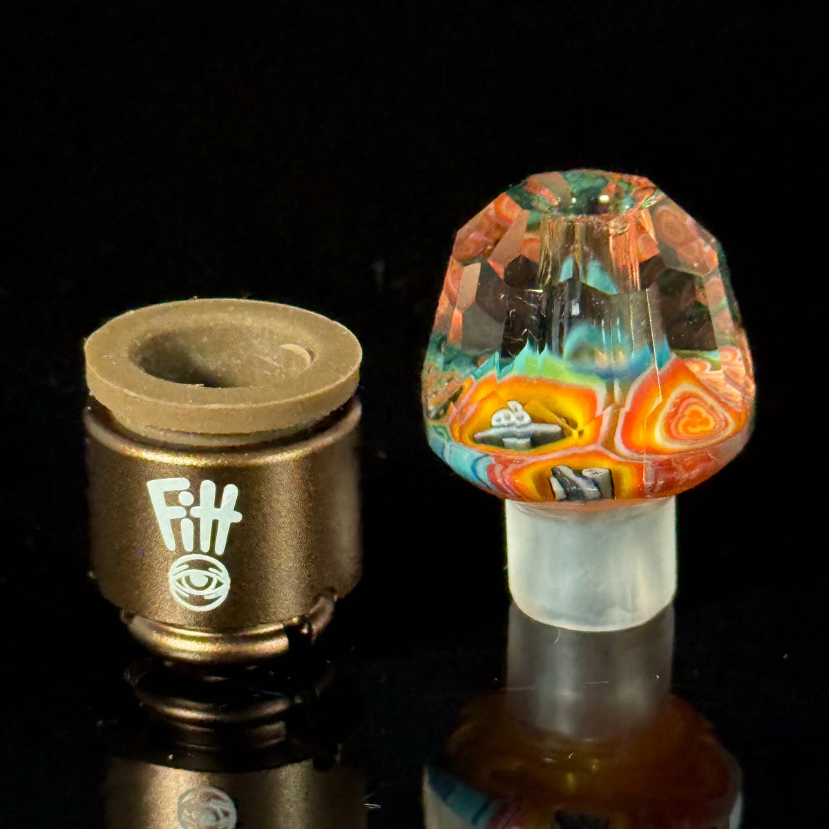 Colorful glass carb cap and brown vaporizer accessory on black background