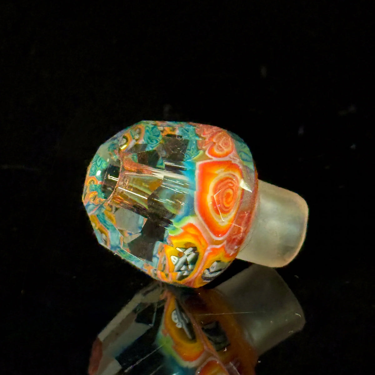 Colorful faceted glass bowl with intricate patterns on a black background