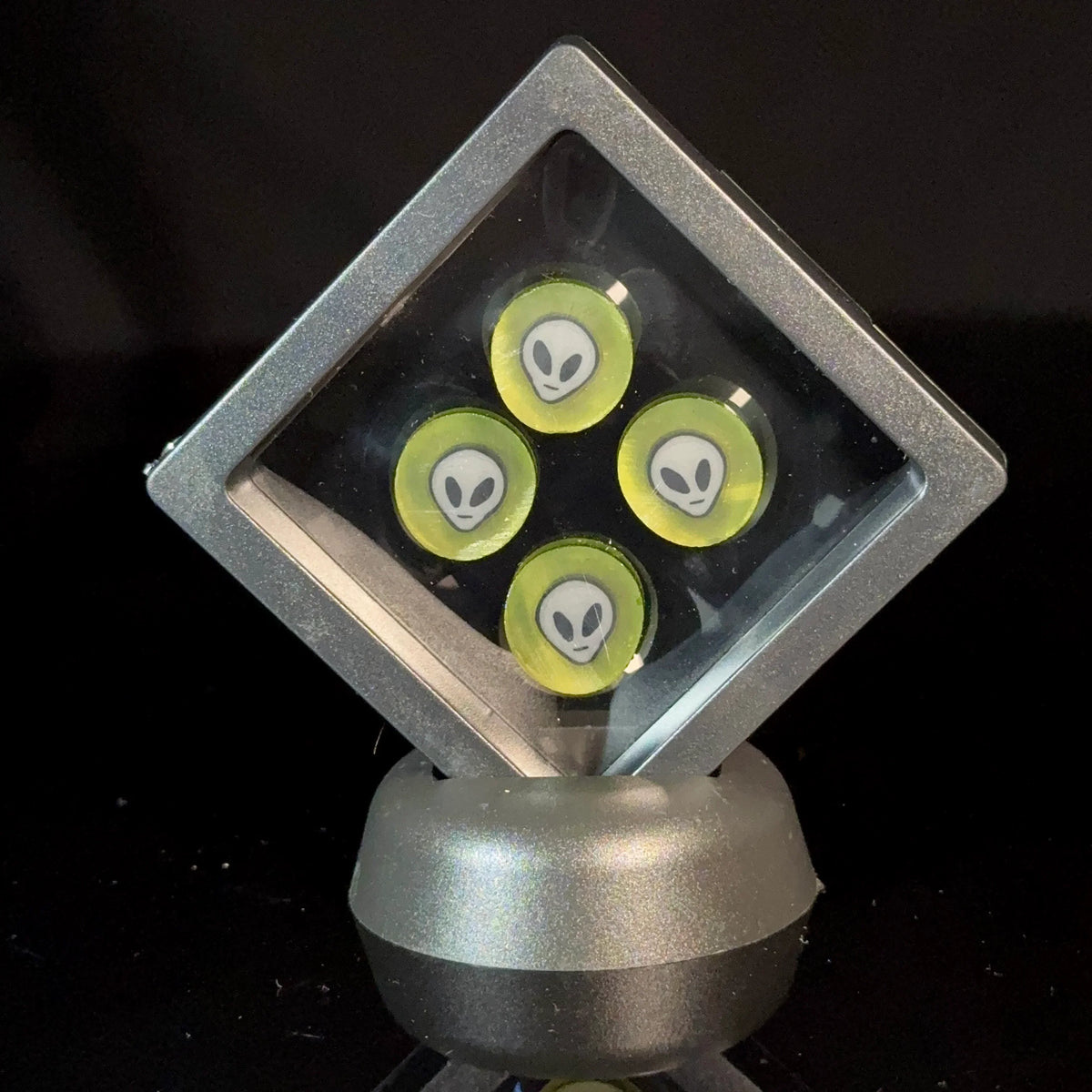 Glass marbles with alien face designs in a display case, black background