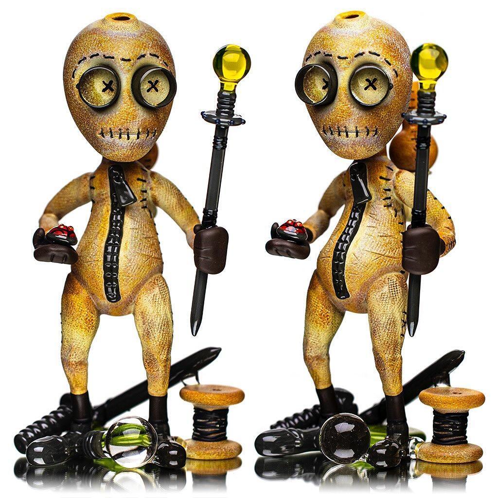Artistic glass figurines resembling stitched dolls with button eyes, holding glass staffs