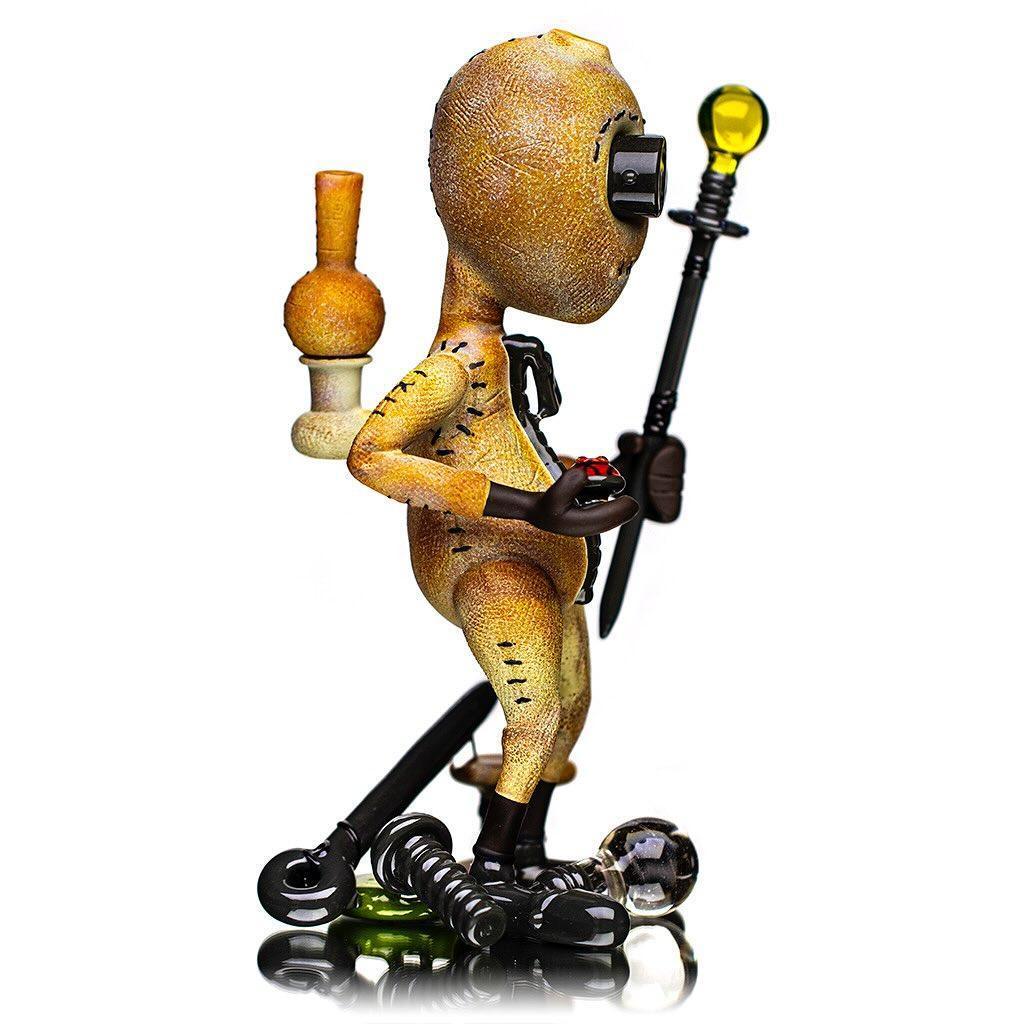 Handcrafted heady glass art figure with staff, stitched detailing, and unique pipe accessory.
