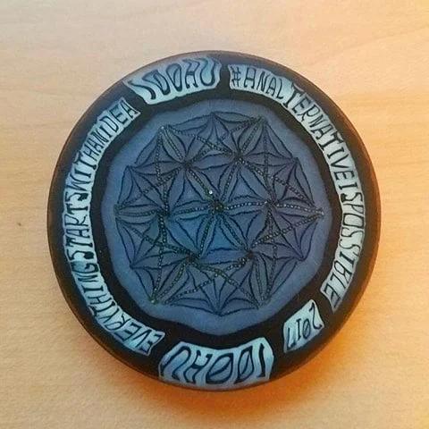 Round glass art piece with geometric flower pattern and inspirational text on a light wood background.