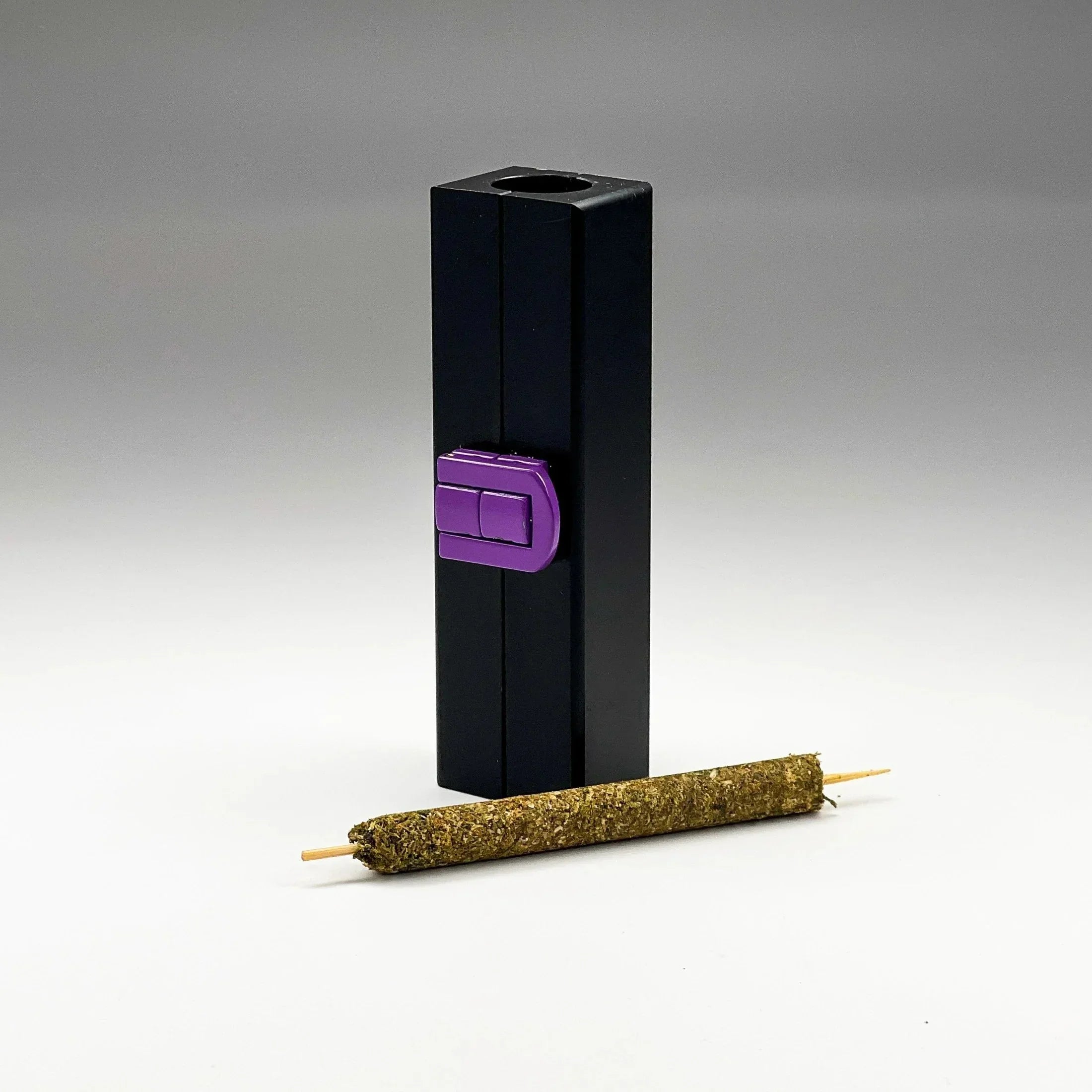 Black joint roller tool with purple latch and a finished pre-roll on a plain background