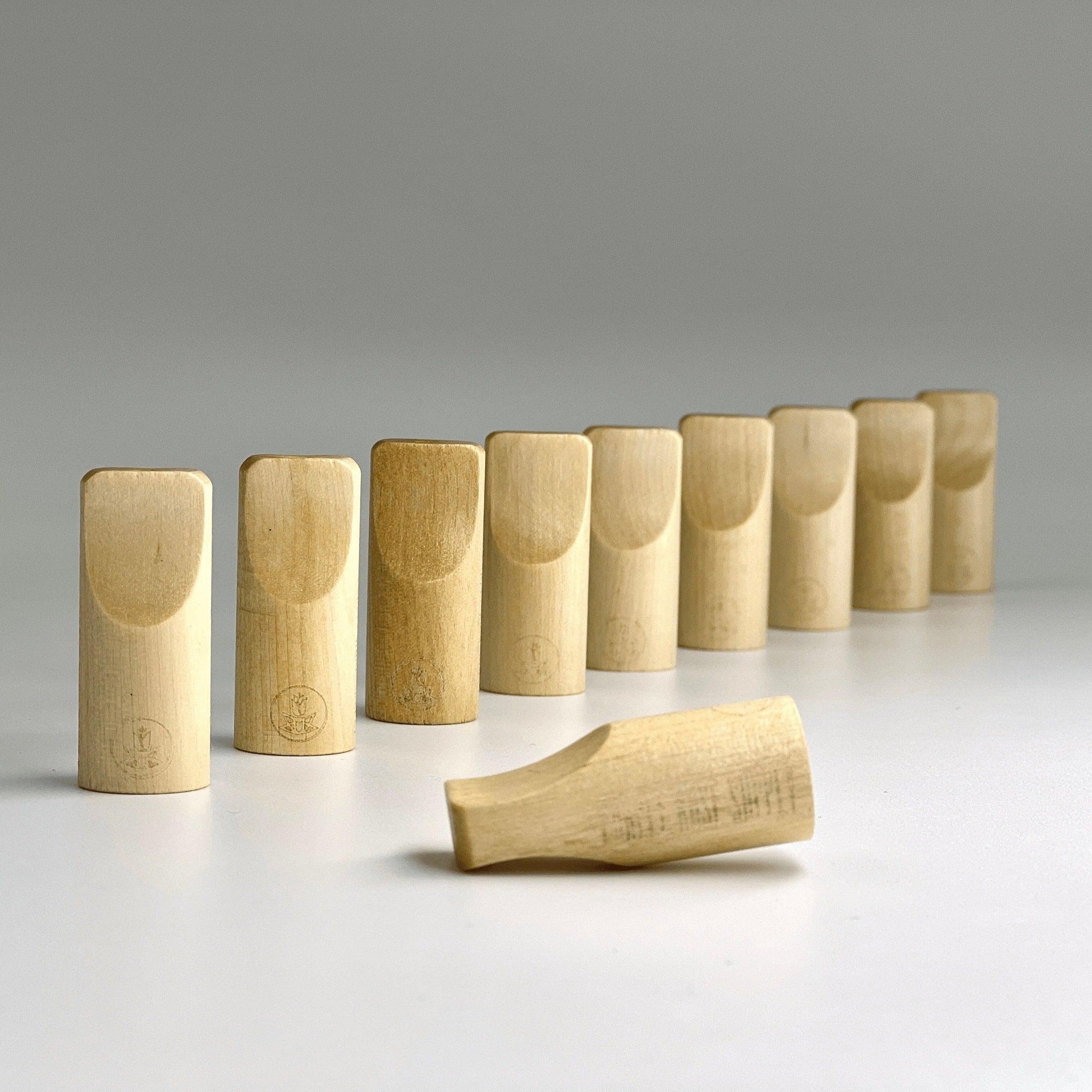 Natural wooden one-hitter pipe tips arranged in a row on a white surface