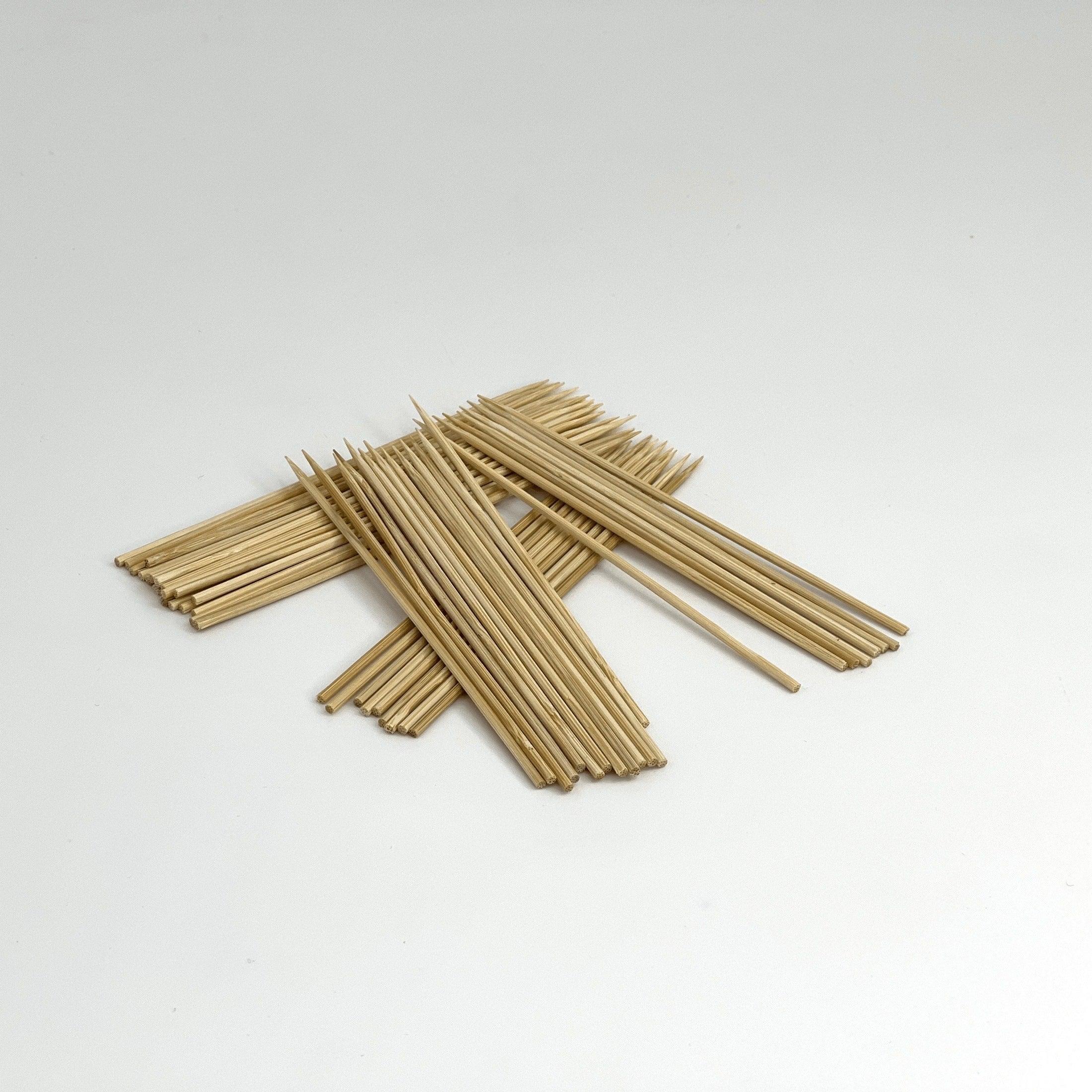 Pile of wooden bamboo skewers with pointed ends on a plain white background