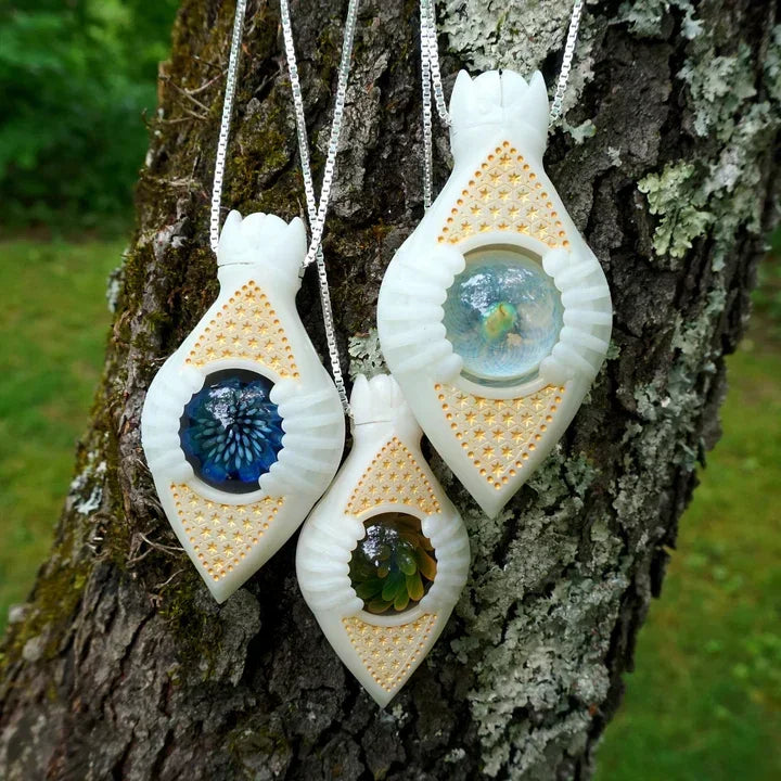 Three intricate glass pendants with colorful floral designs, hanging on a tree outdoors.