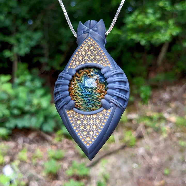 Intricate glass pendant necklace with geometric patterns and colorful center orb outdoors