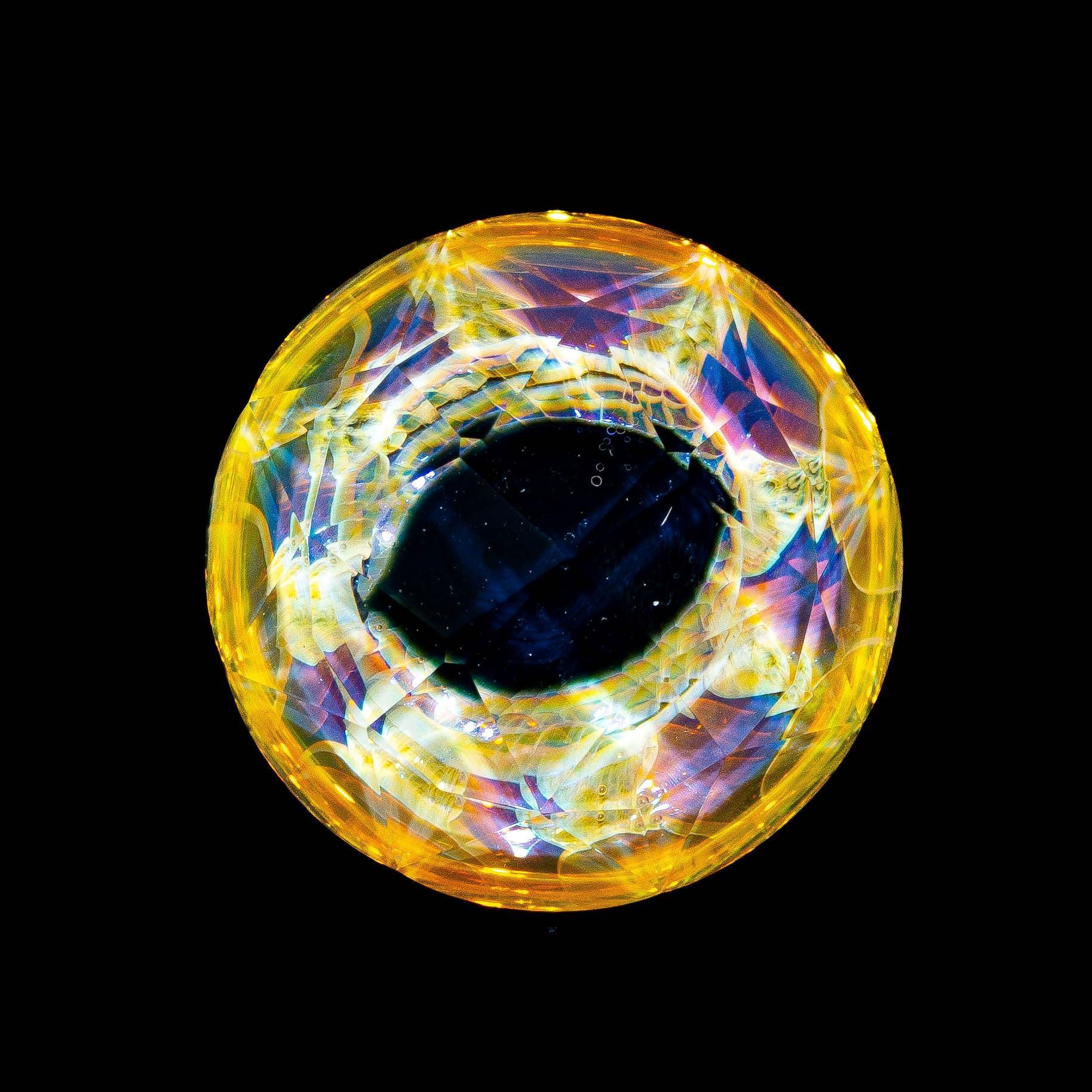 Intricate multicolor glass marble with yellow and blue patterns on a black background.