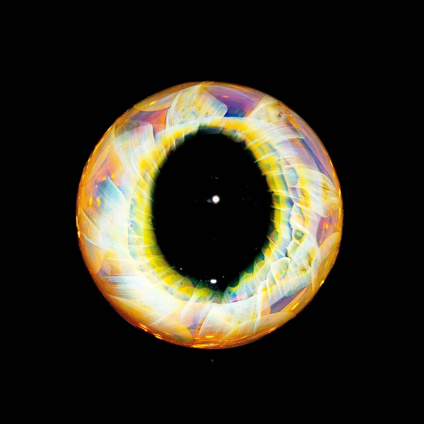 Colorful glass marble with intricate eye pupil design on a black background