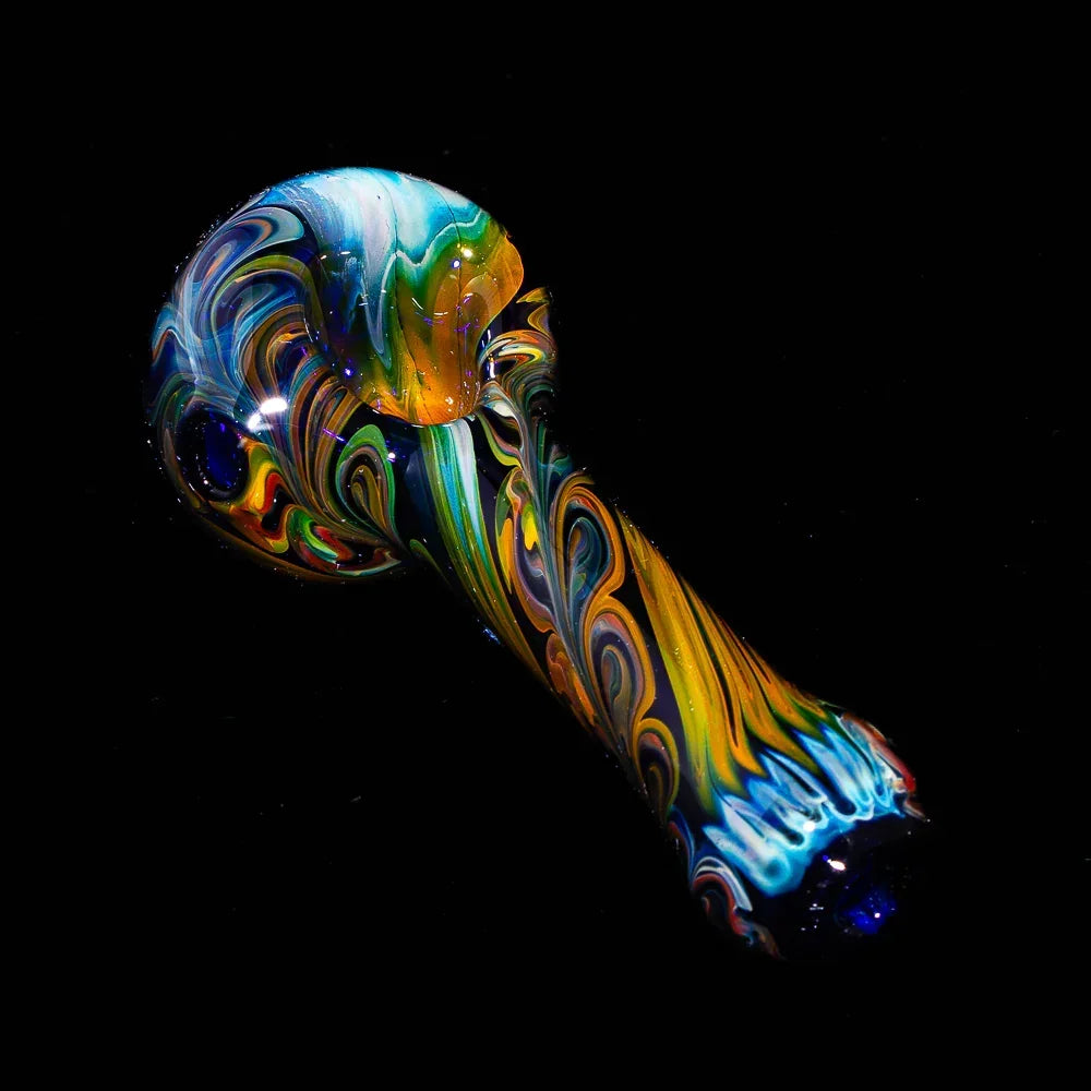 Colorful blue and yellow paisley glass pipe with intricate linework on black background