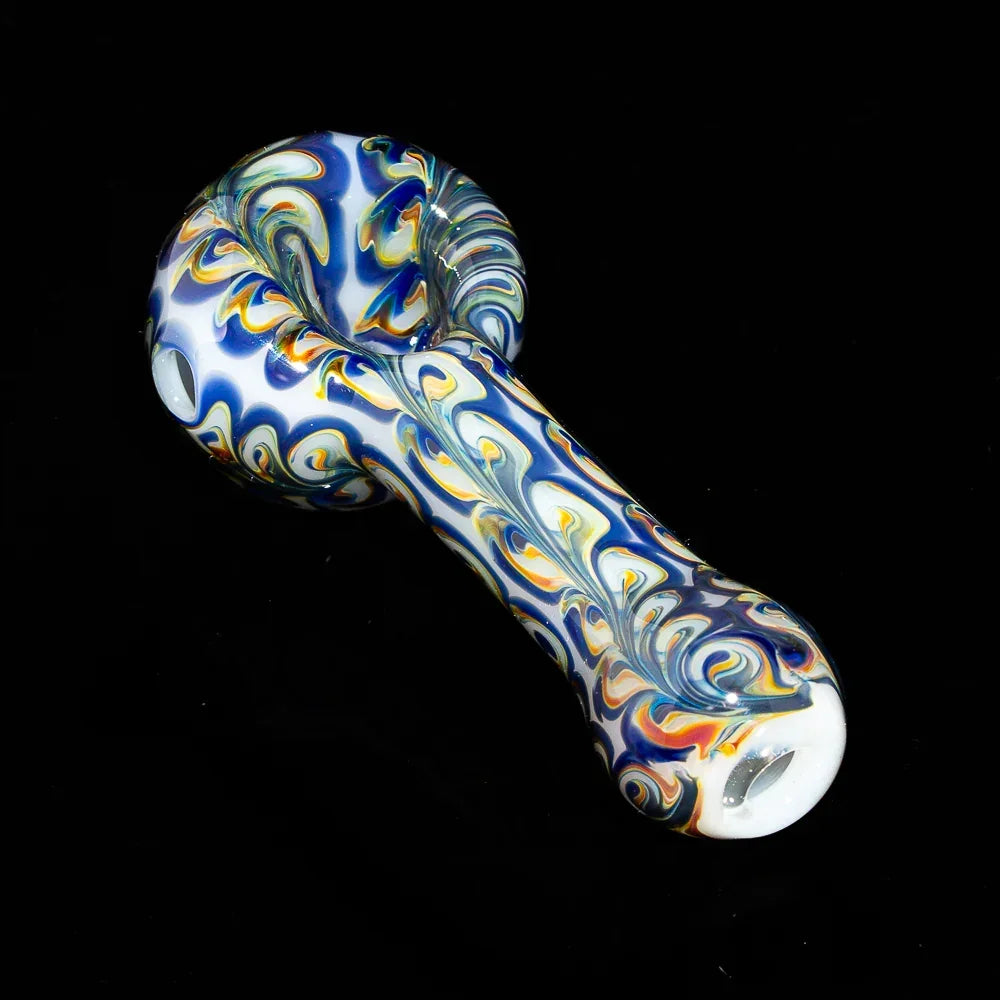 Blue and yellow paisley glass spoon pipe with intricate pattern on black background