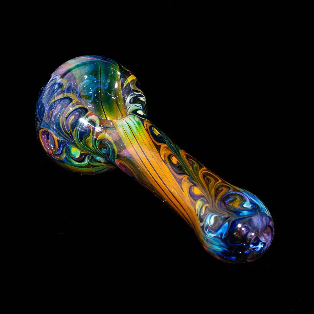 Colorful fumed glass spoon pipe with blue paisley linework on a black background.