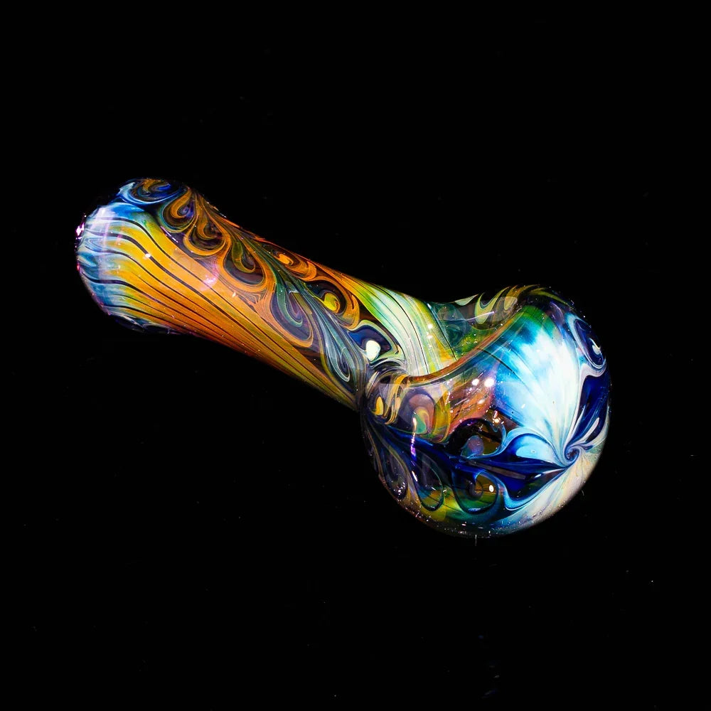 Fumed glass spoon pipe with blue paisley linework on black background