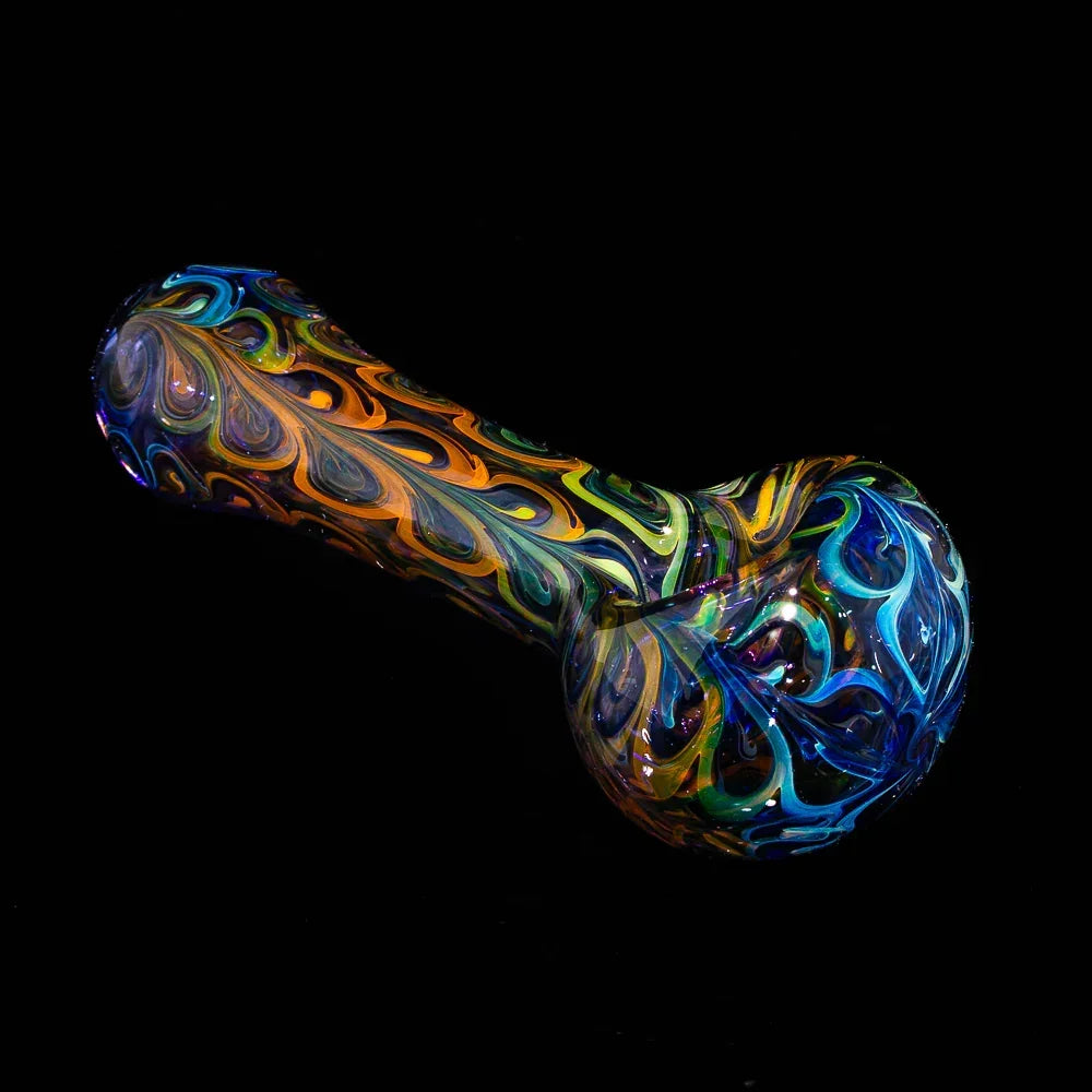 Colorful fumed glass spoon pipe with blue paisley patterns on a black background