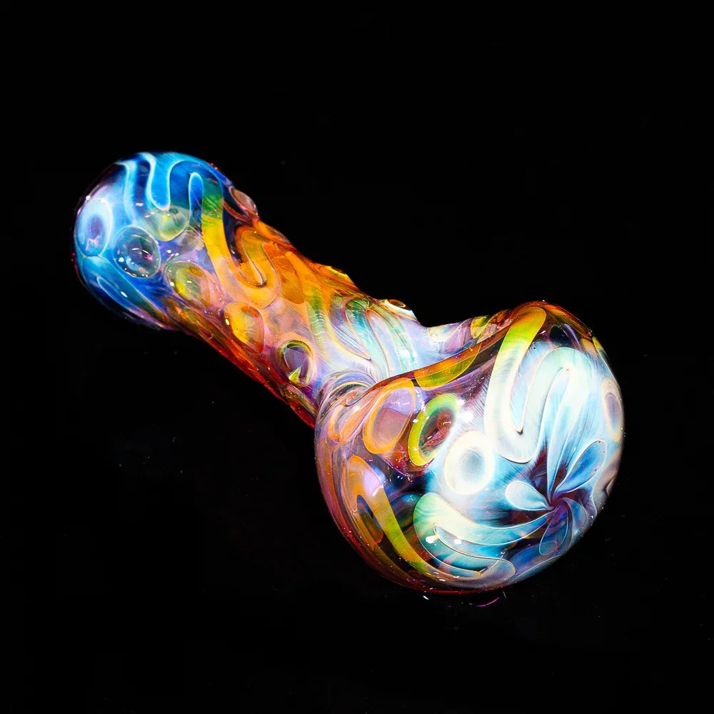 Colorful fumed glass spoon pipe with swirling scribble patterns on a black background