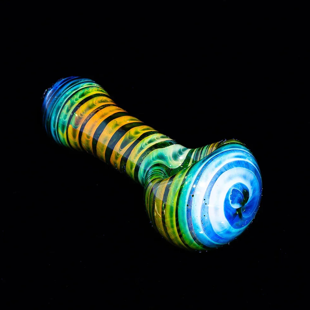 Green and yellow fumed glass spoon pipe with spiral coil design on a black background