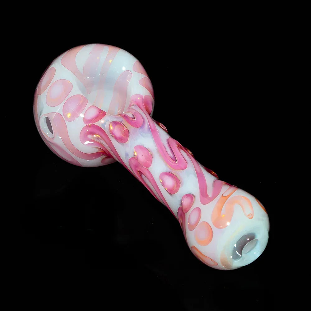 Handblown glass pipe with pink and orange scribble design on a white base, displayed on black background.