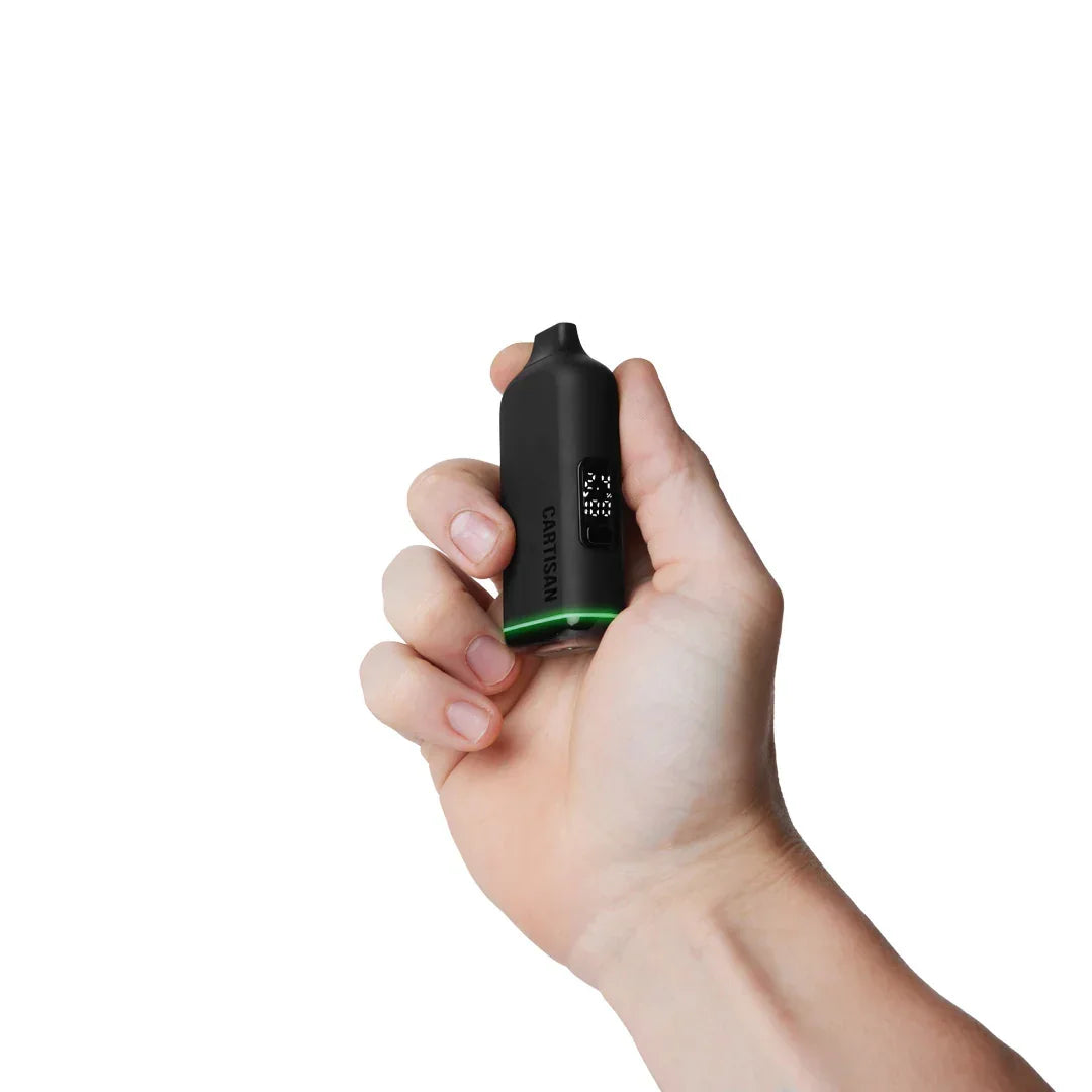 Hand holding a black Cartisan vaporizer with LED light on white background