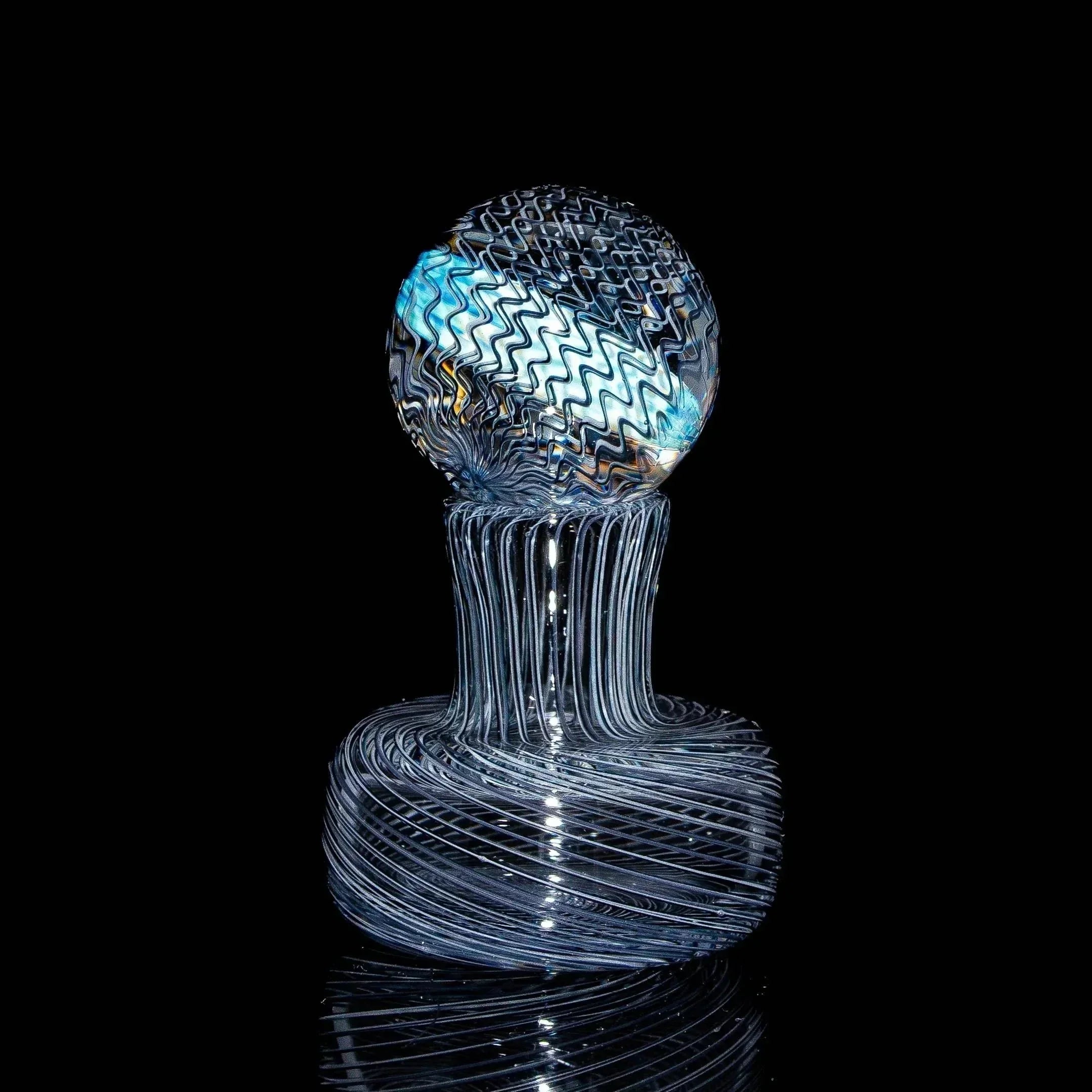 Hand-blown glass marble with intricate swirling patterns on a black background