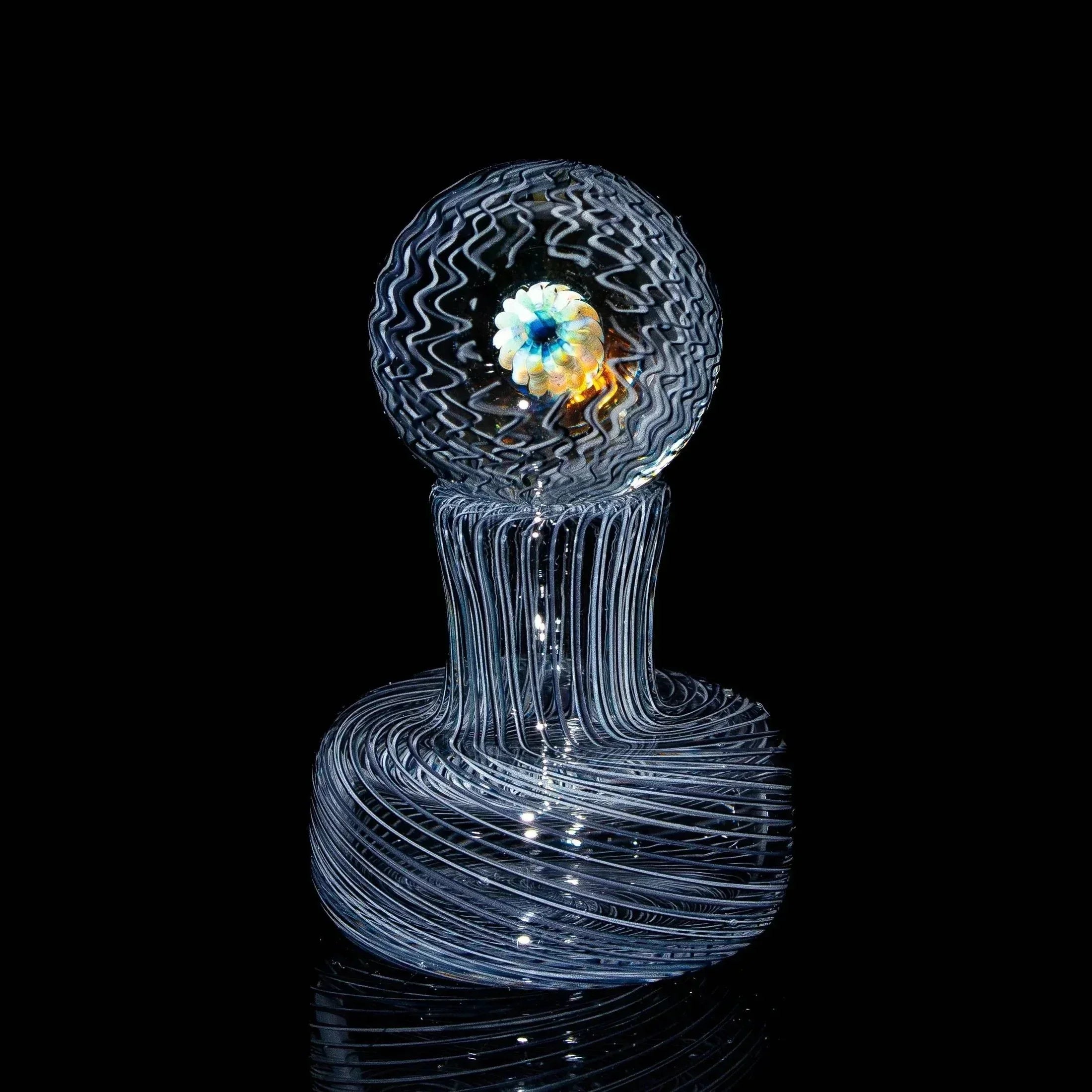 Clear art glass marble with swirling patterns and a flower design center on black background