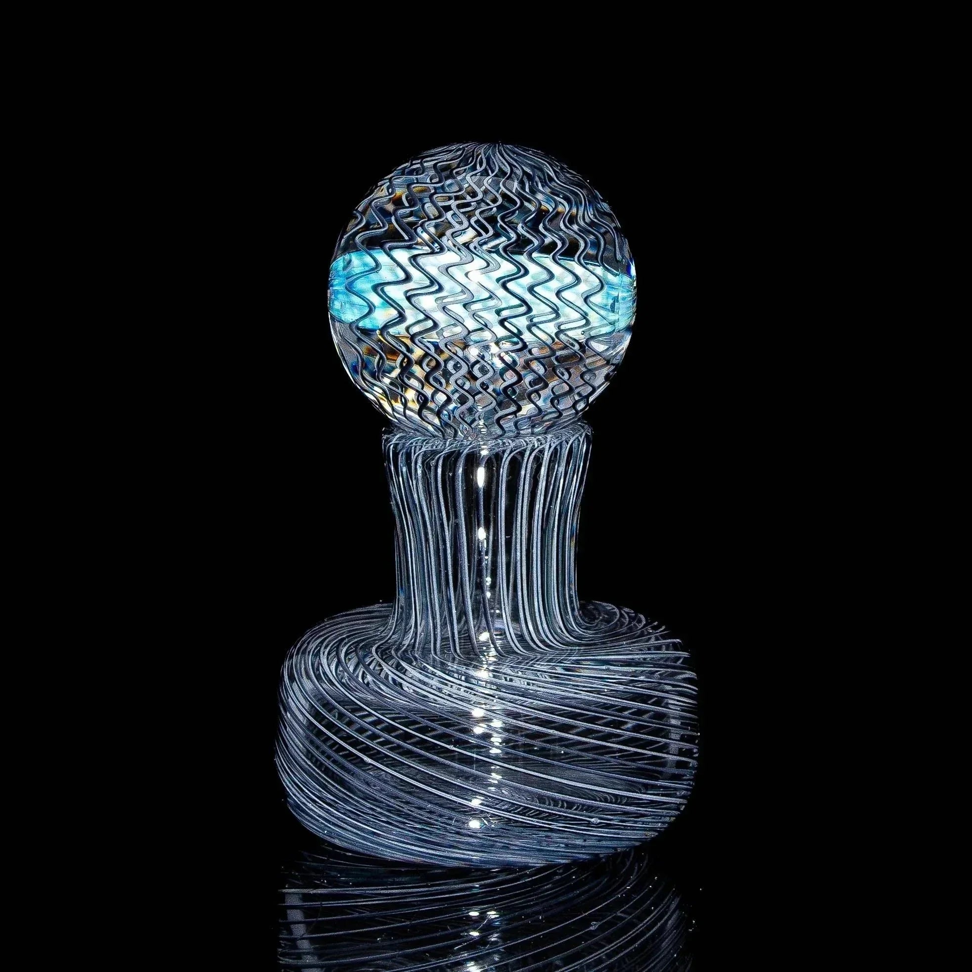 Handblown glass marble with intricate swirled patterns on a black background