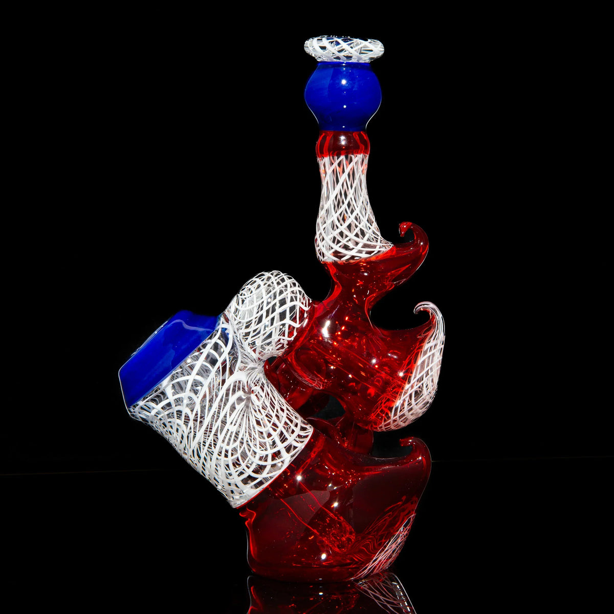 Colorful red, blue, and white glass bubbler with intricate patterns on black background.