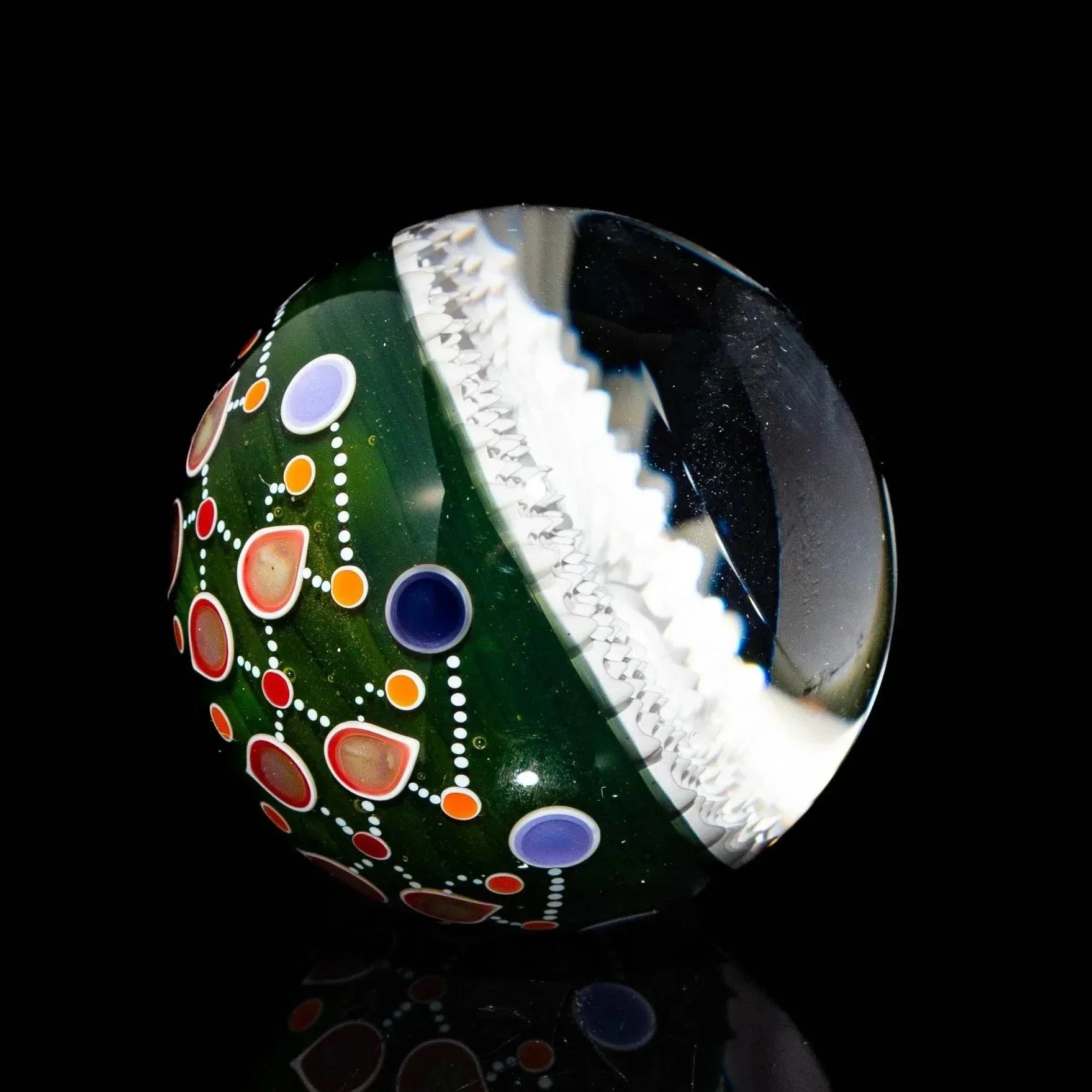 Handcrafted reticello glass marble with green base, colorful dots, and intricate designs