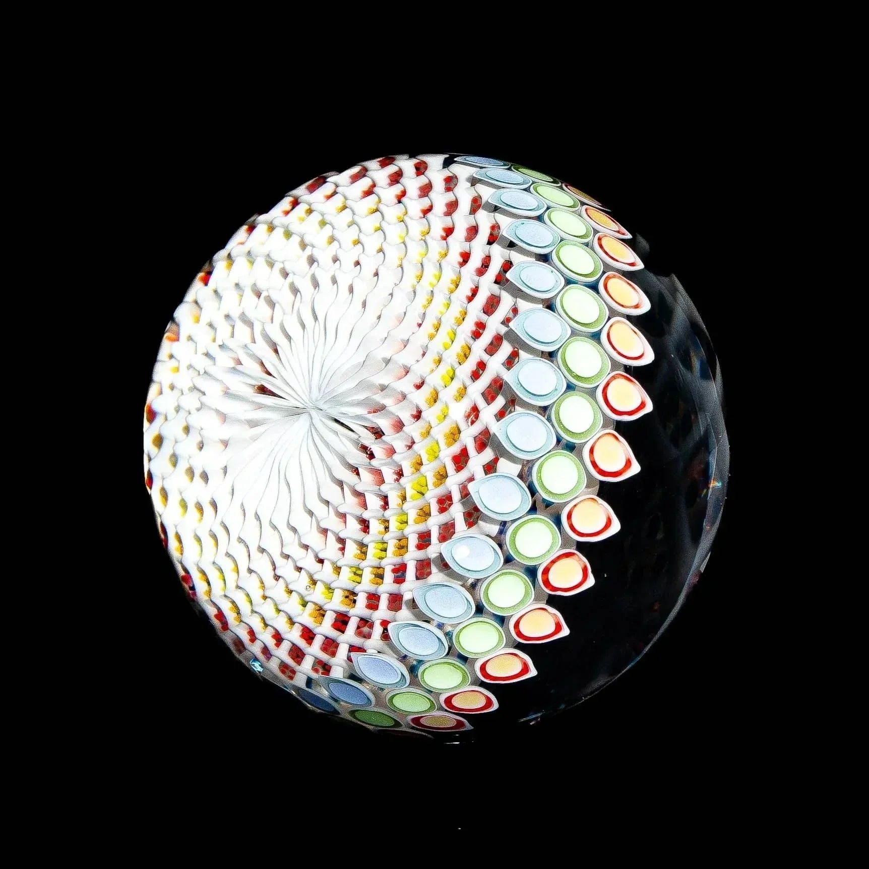 Colorful glass marble with intricate spiral and dot patterns on black background