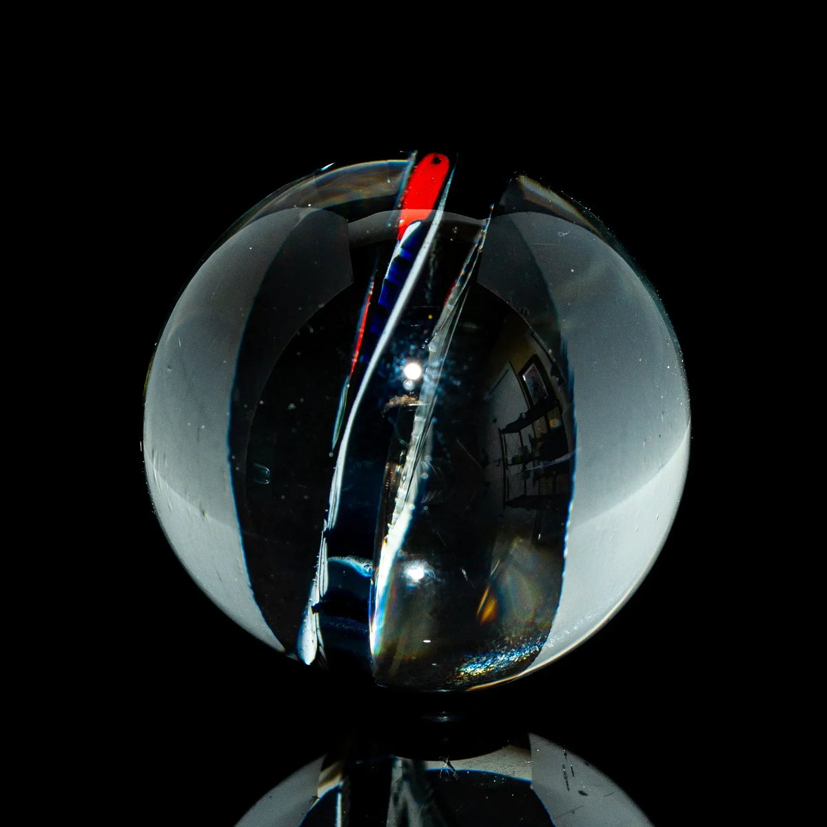 Clear glass marble with intricate colored swirl on black background