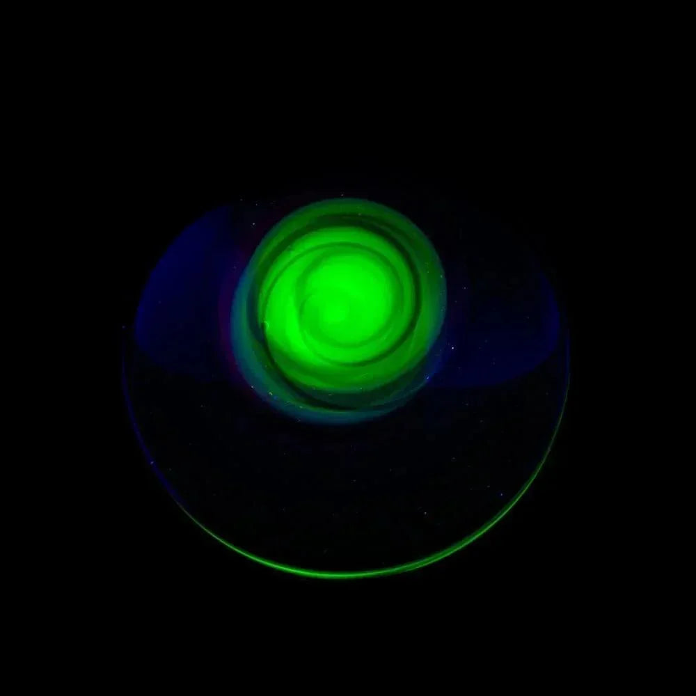 Glowing green glass marble with spiral design on a black background.