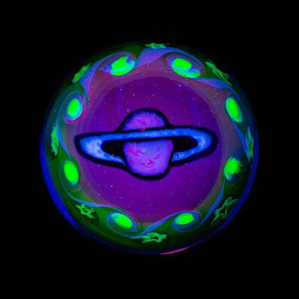 UV reactive glass marble featuring a glowing planet and cosmic designs on black background