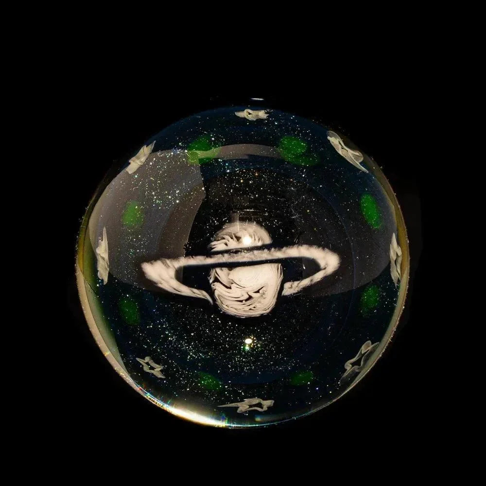 Handcrafted glass marble with a space-inspired design featuring a ringed planet and stars